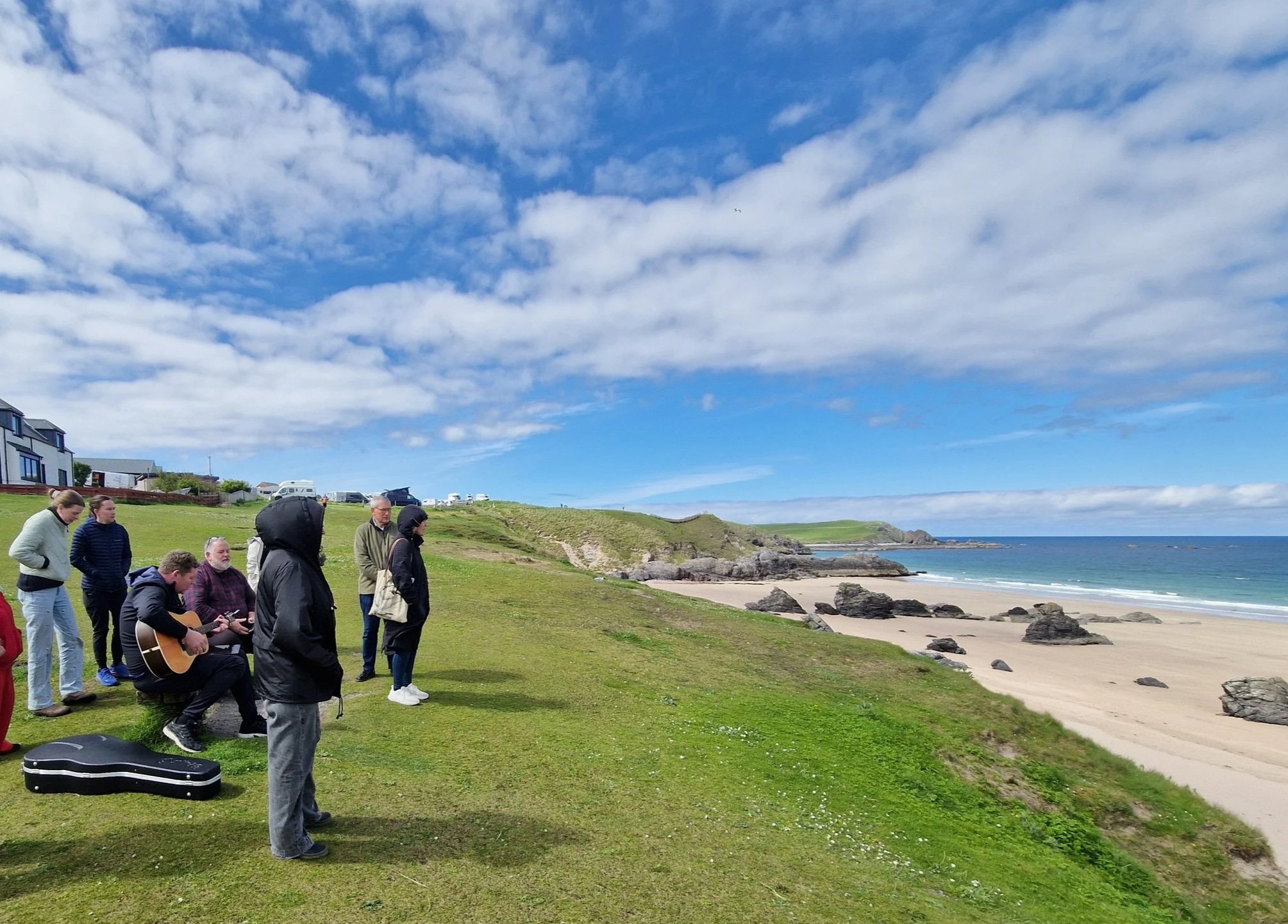 A group of people looking out towards a coastline from a cliff face.
