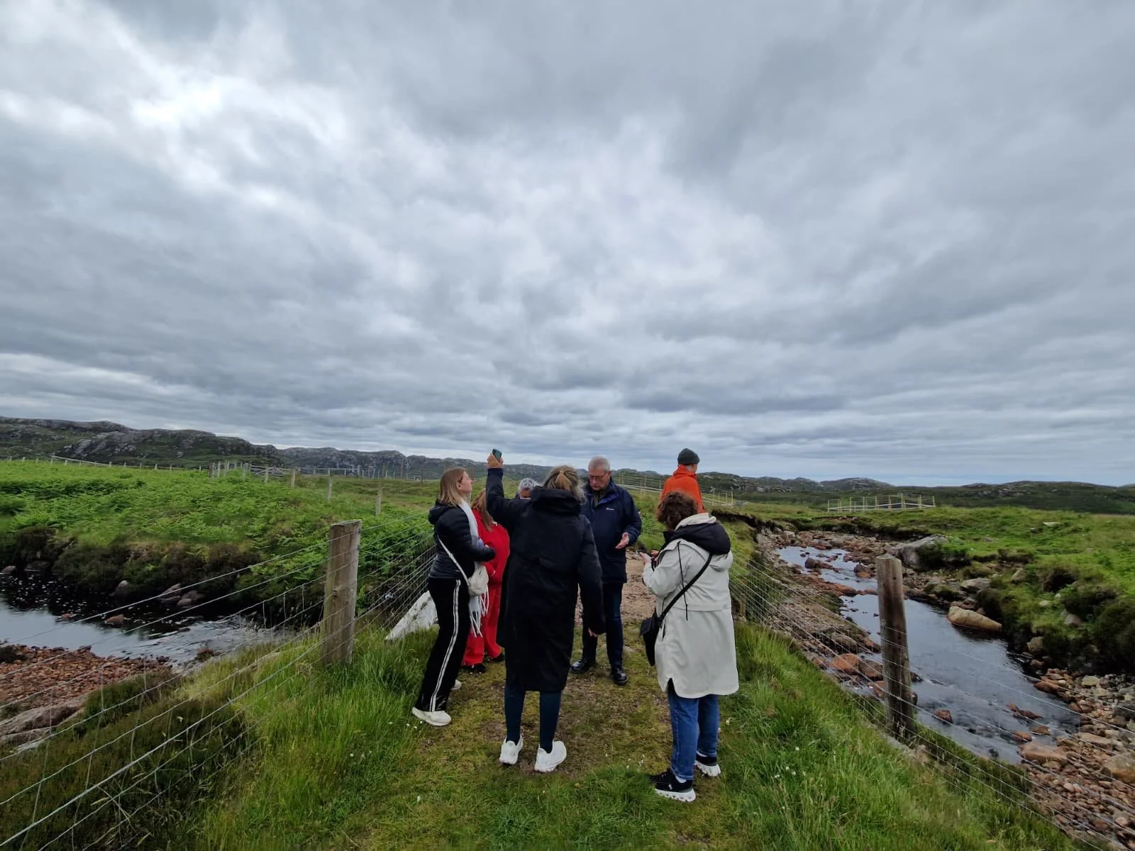 A small group of people standing in a field praying together over the land.