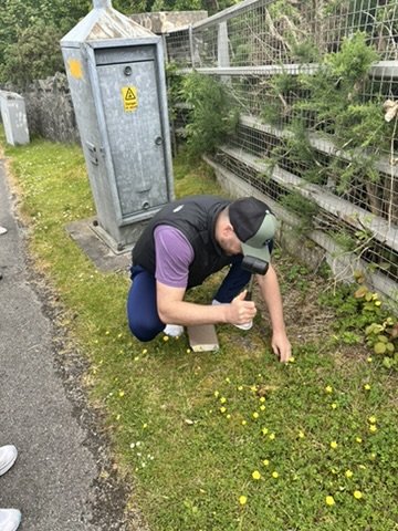A man holding a rubber mallet hammering something into the ground.