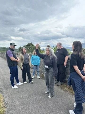 One woman is holding up her hand with her eyes closed, while a team stands around her in support.