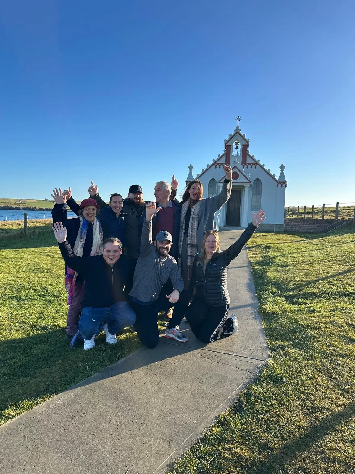 An outreach team standing outside of a church cheering as they pose for a photo.