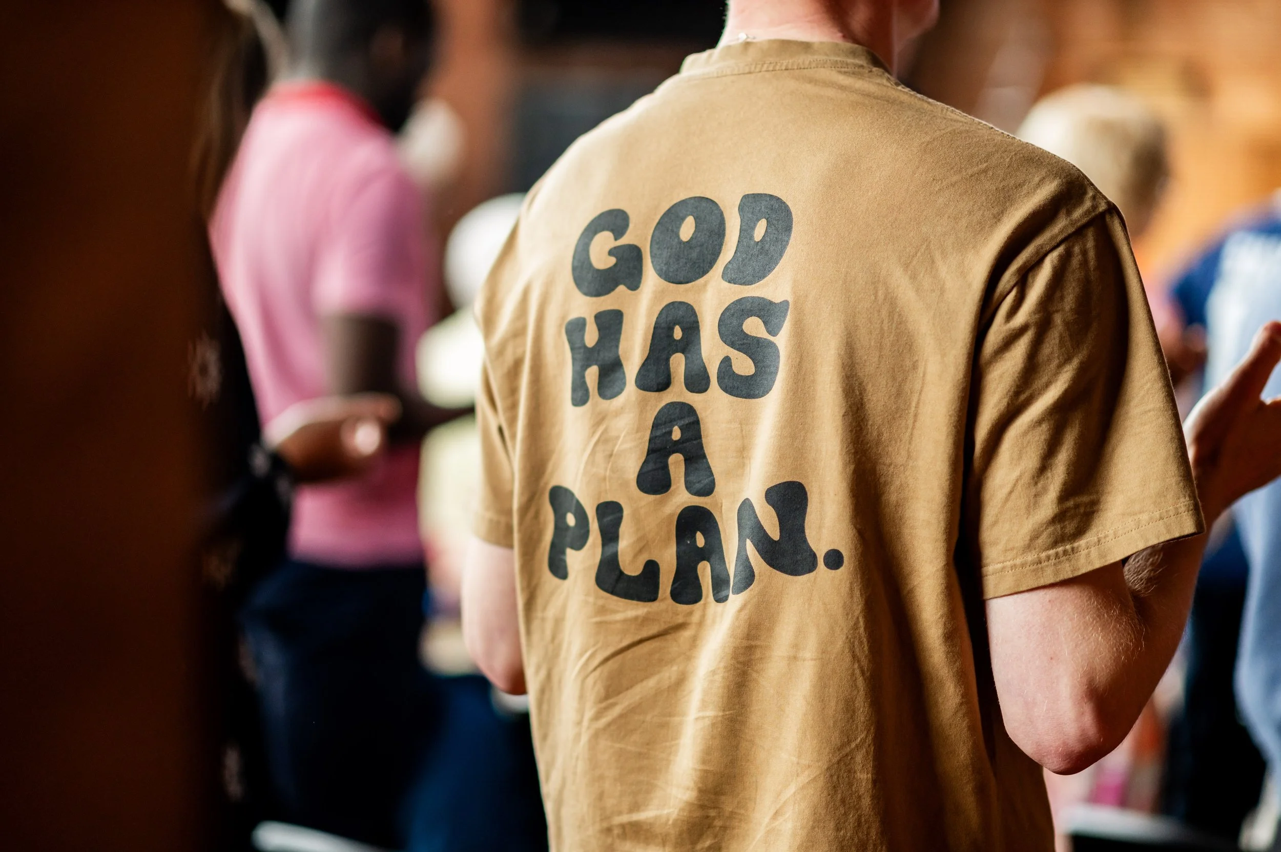The back of a t-shirt that someone is wearing that has the words "God has a plan" on it,