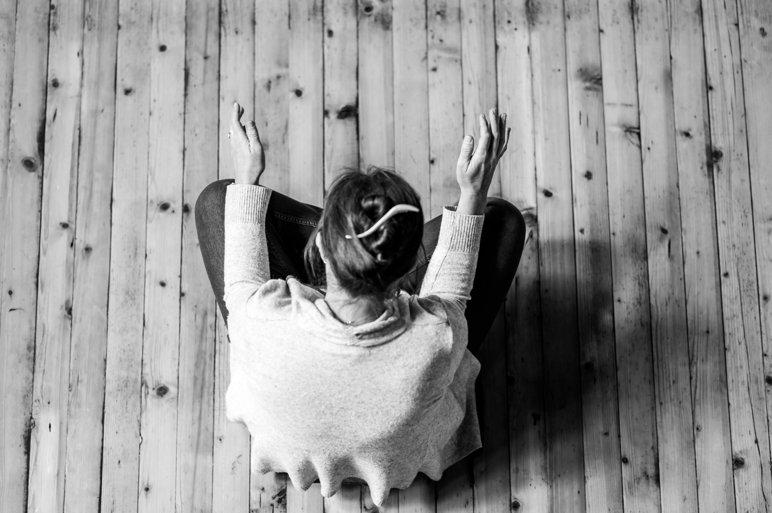an top down perspective of a woman sitting crossed-legged praying.