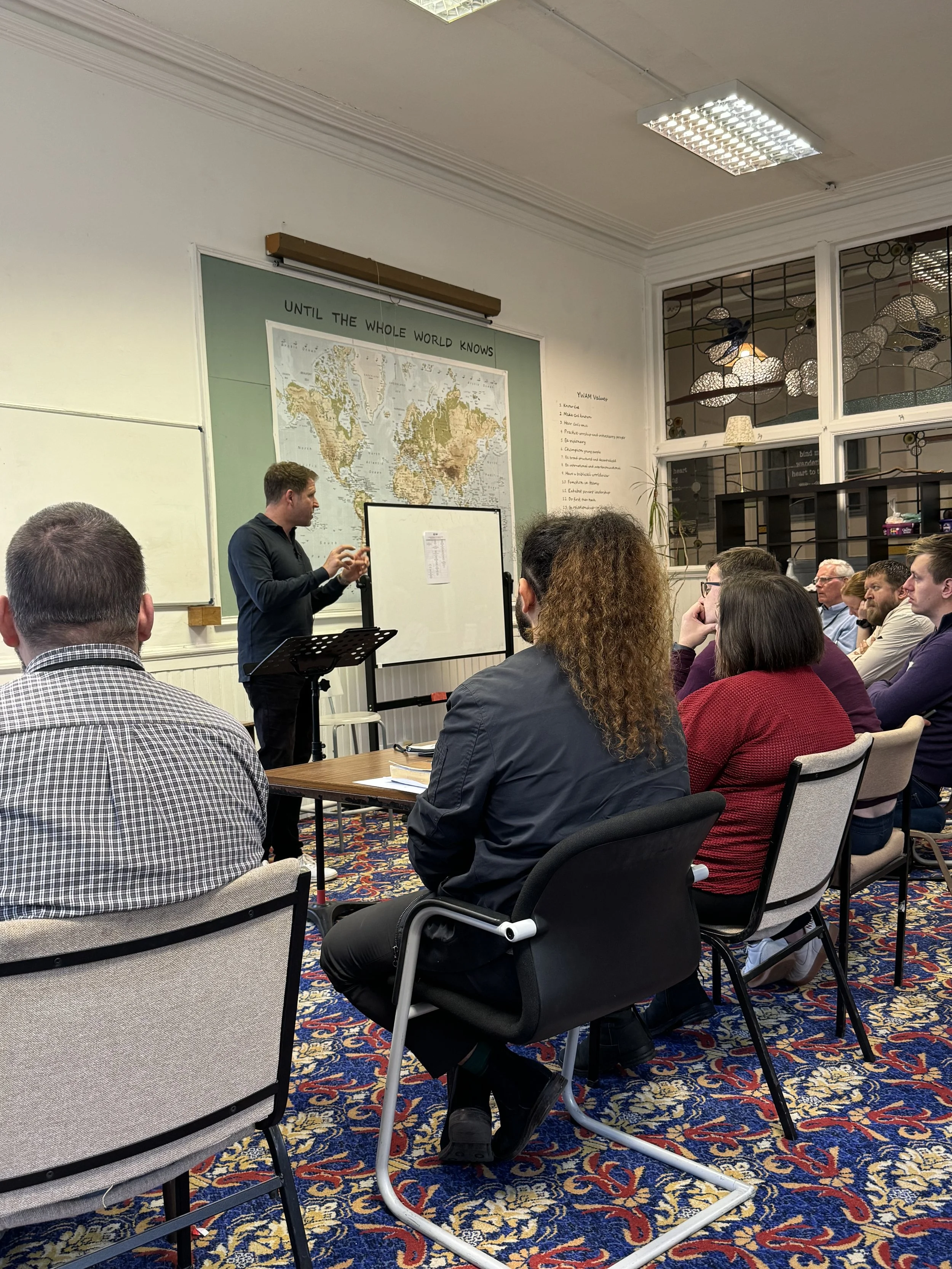Peter Anderson teaching at Forge 3, to a group of looking at a whiteboard he's teaching from.