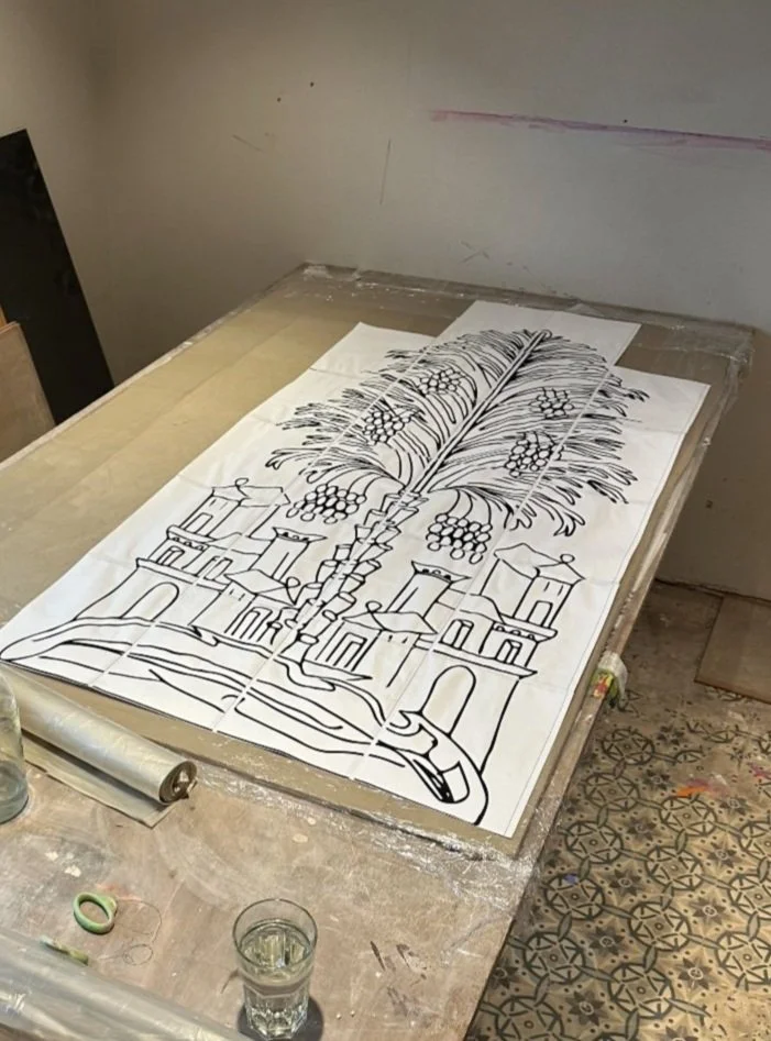 Plan ou esquisse d'une architecture avec des palmiers et une ville en arrière-plan, réalisé sur une grande feuille posée sur une table.