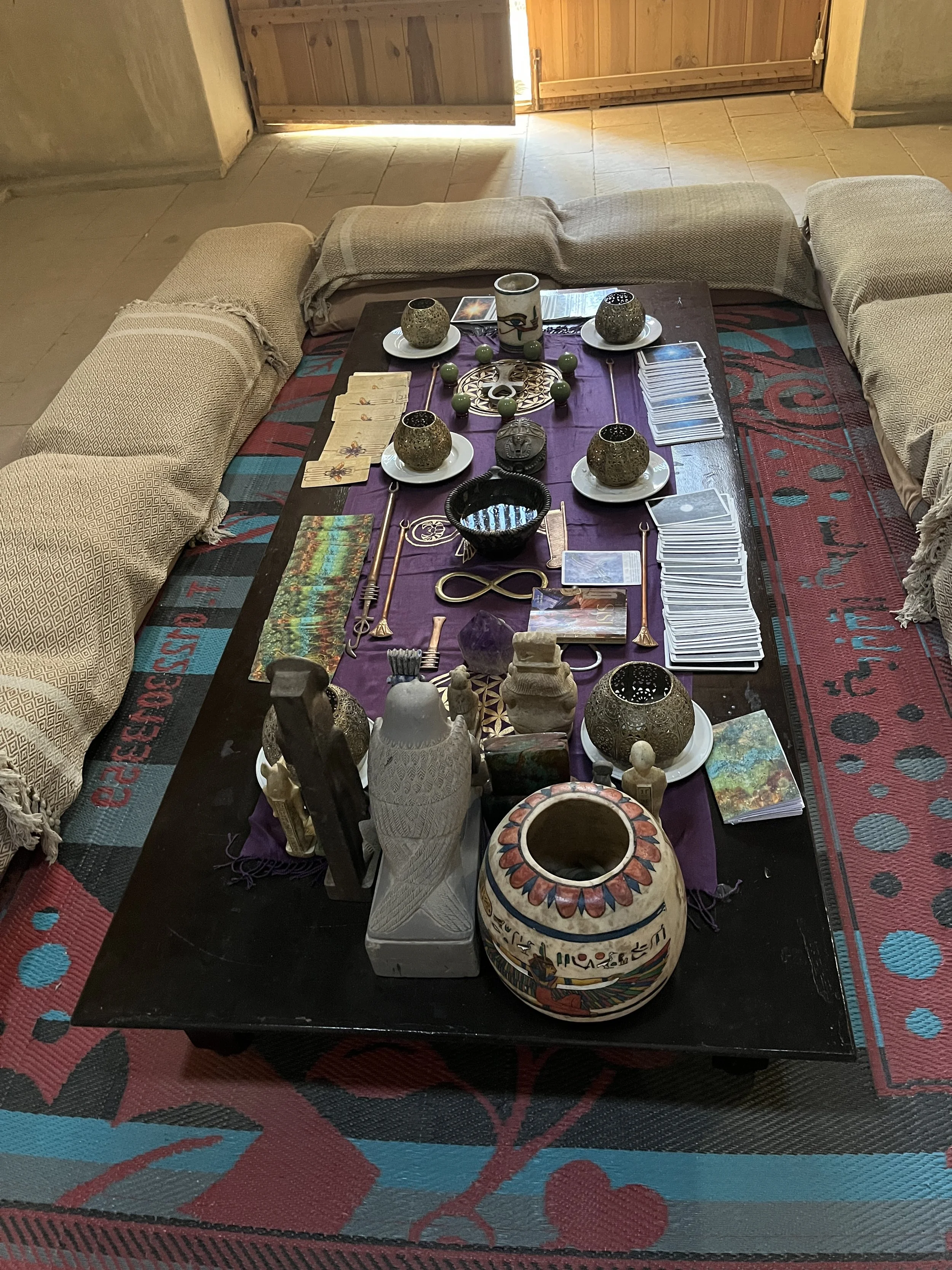 Sacred ceremony setup with oracle cards, candles and Egyptian statues at House of Life Abydos during a spiritual healing retreat