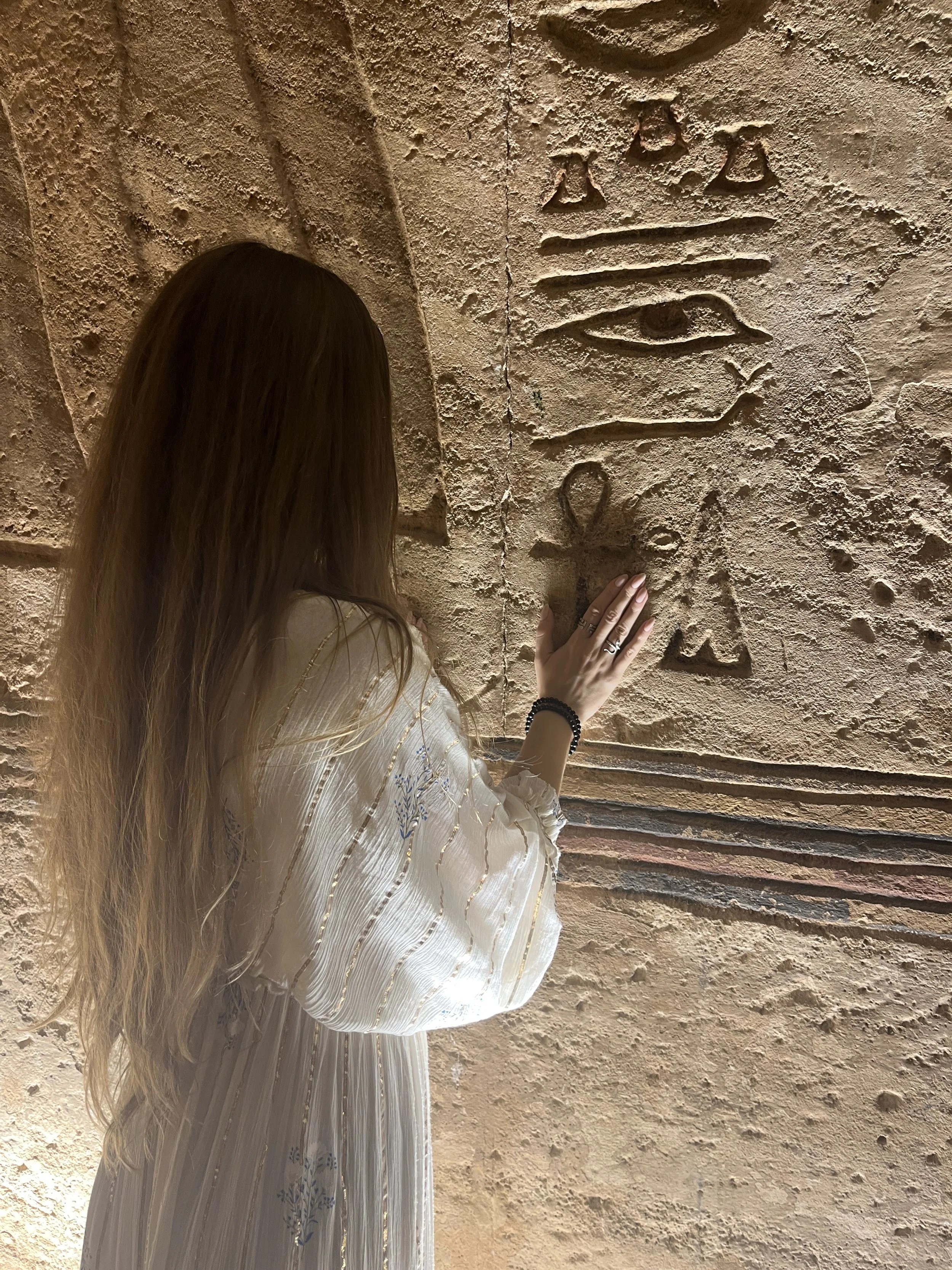 Woman touching an ankh symbol inside an ancient Egyptian temple during a sacred initiation experience.