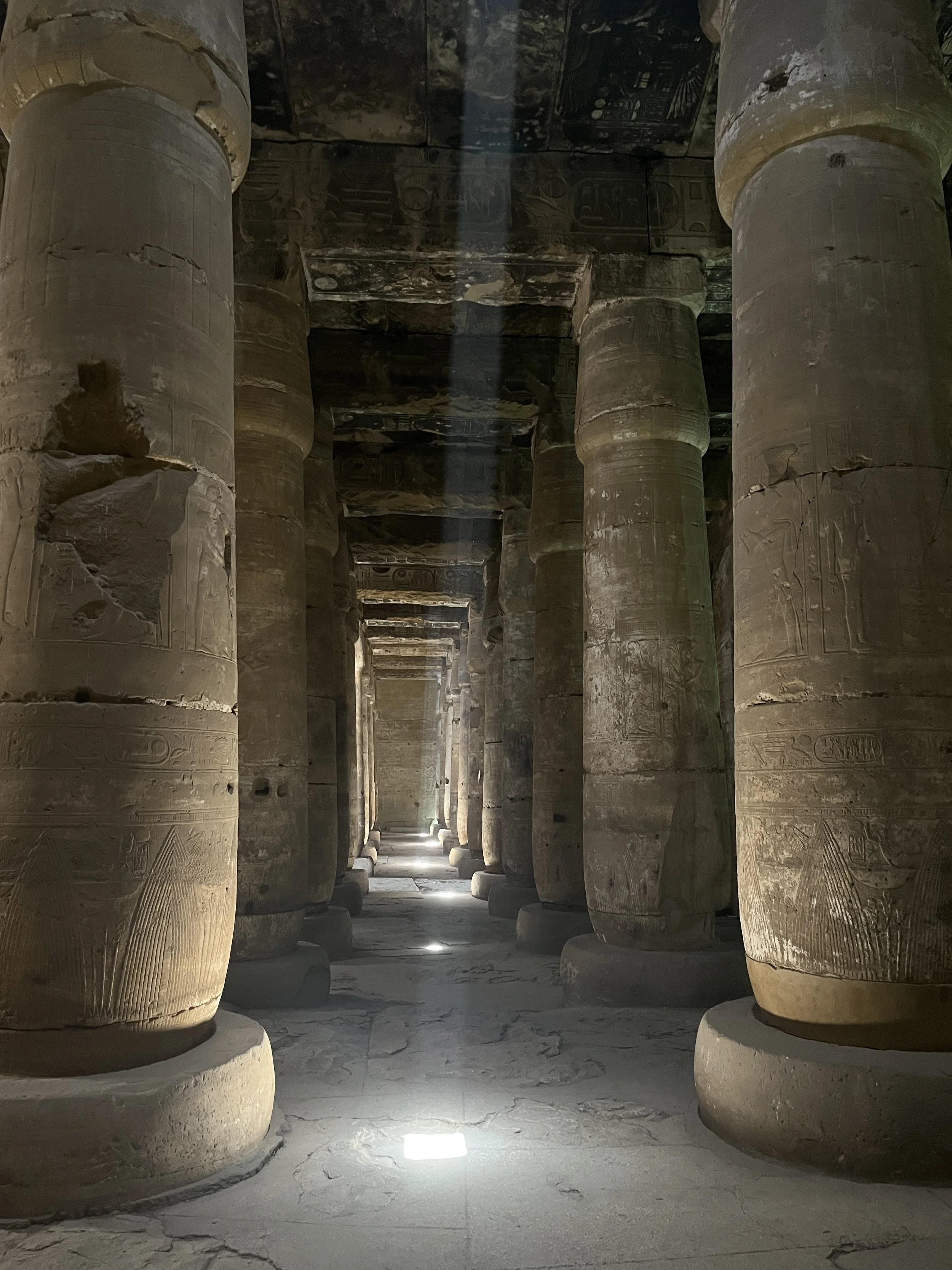 Interior of the Temple of Seti I at Abydos showing ancient carved columns and hieroglyphs with beams of light
