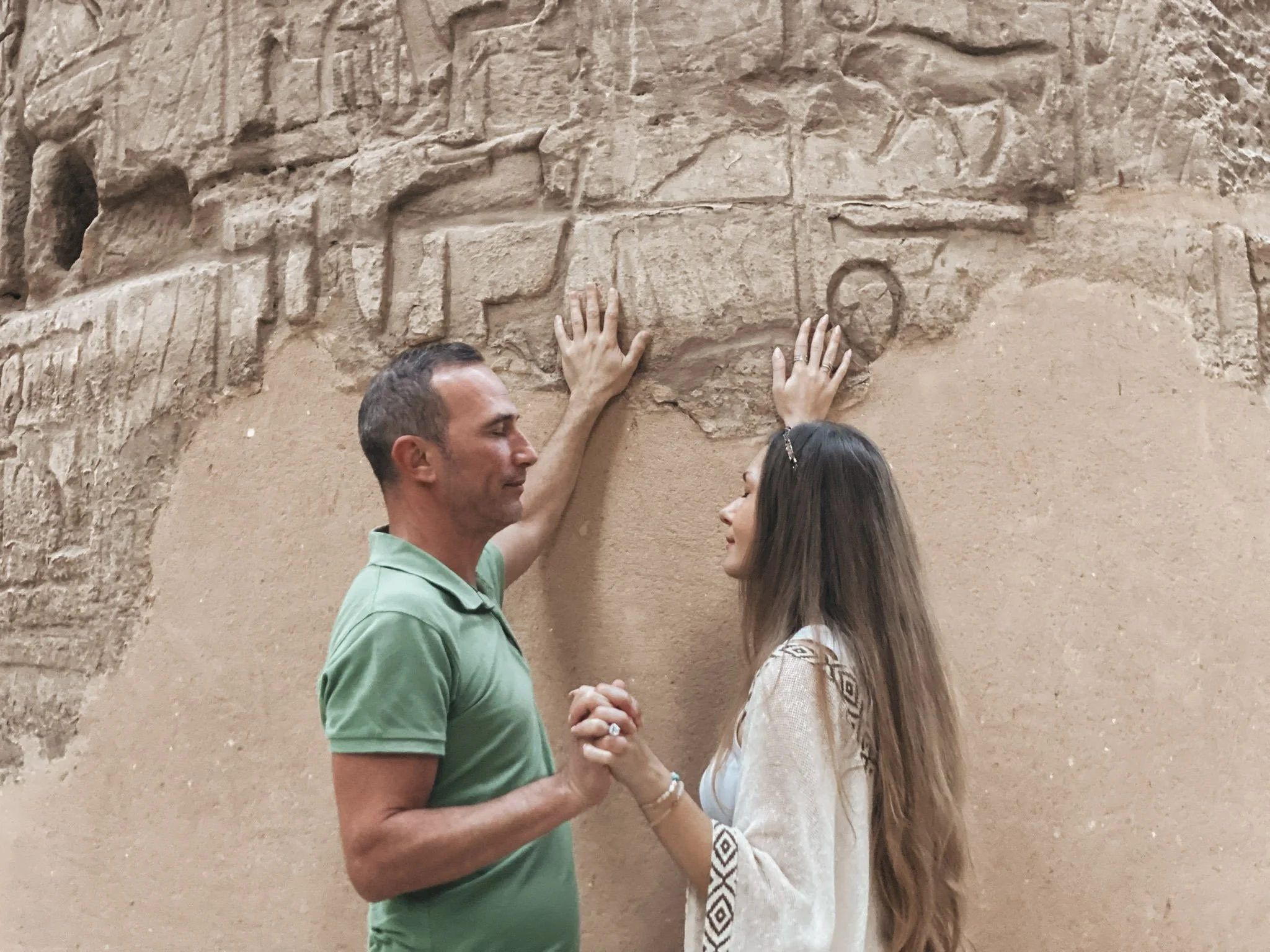 Sabina and Leo touching ancient Egyptian hieroglyphs together, hands joined, KA Light Activation co-facilitators in sacred connection