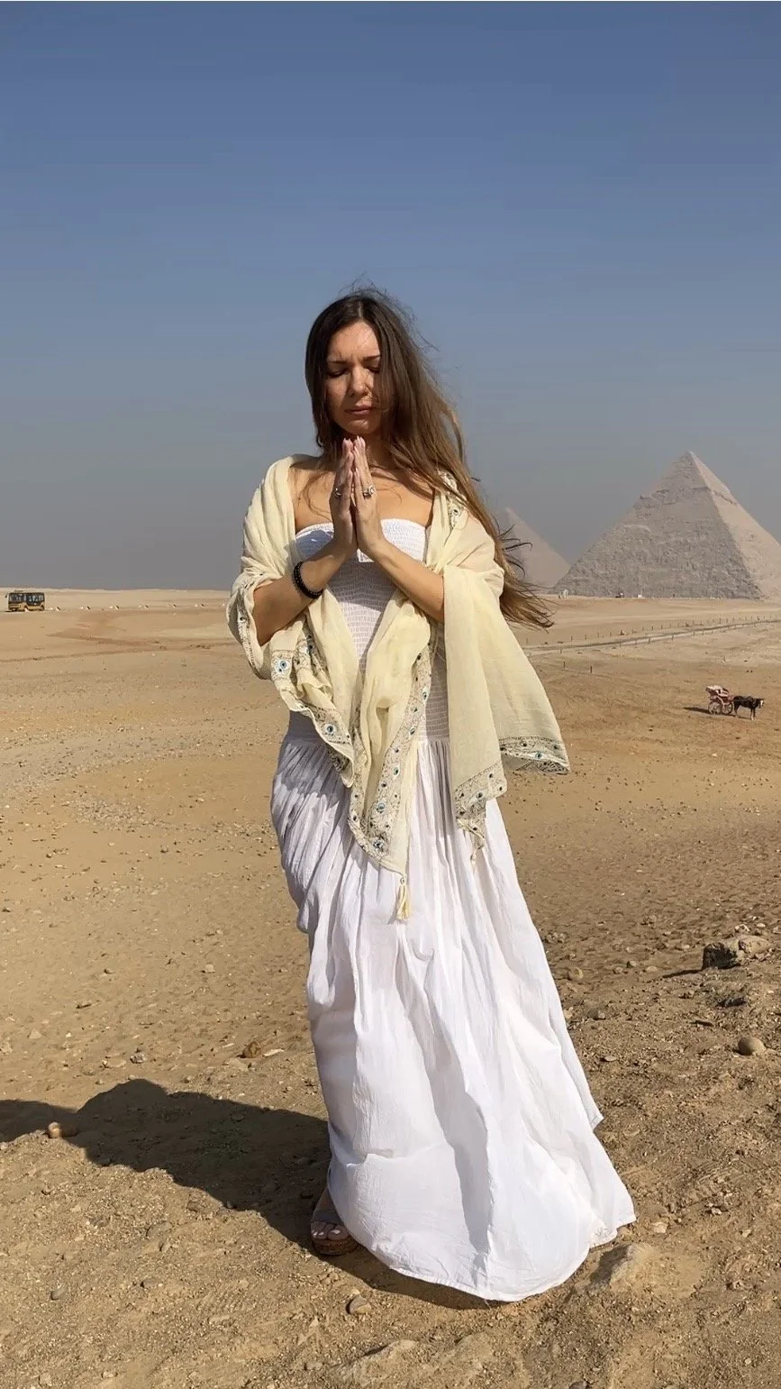 Woman in meditation pose near the Great Pyramids of Giza during a spiritual retreat in Egypt.
