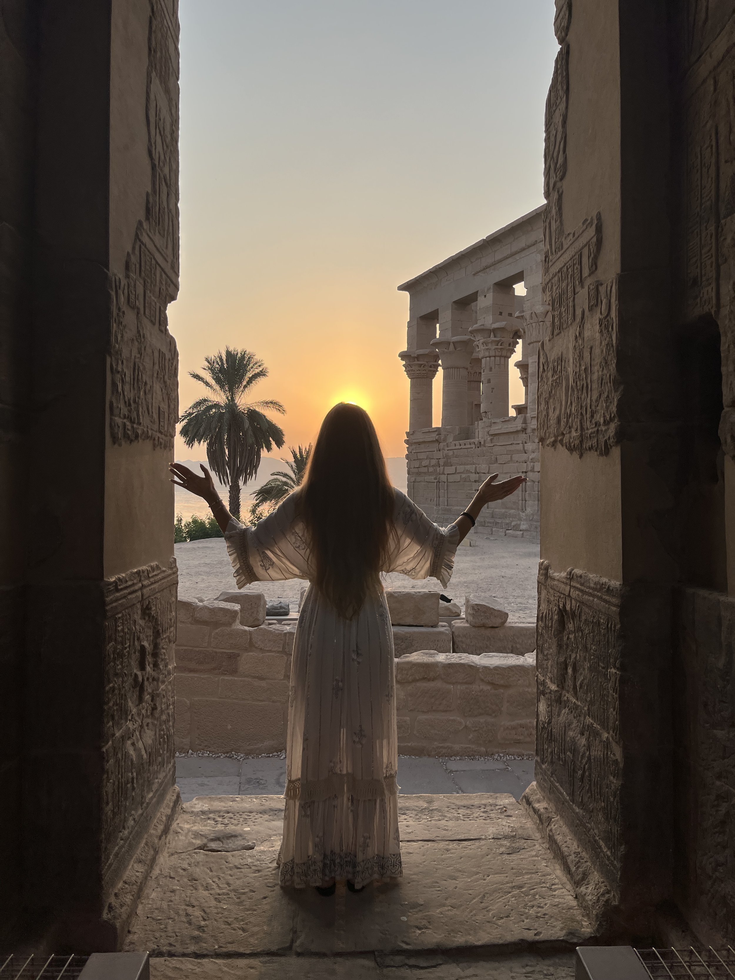 Woman standing at Philae temple in Egypt at sunrise during a sacred initiation journey.