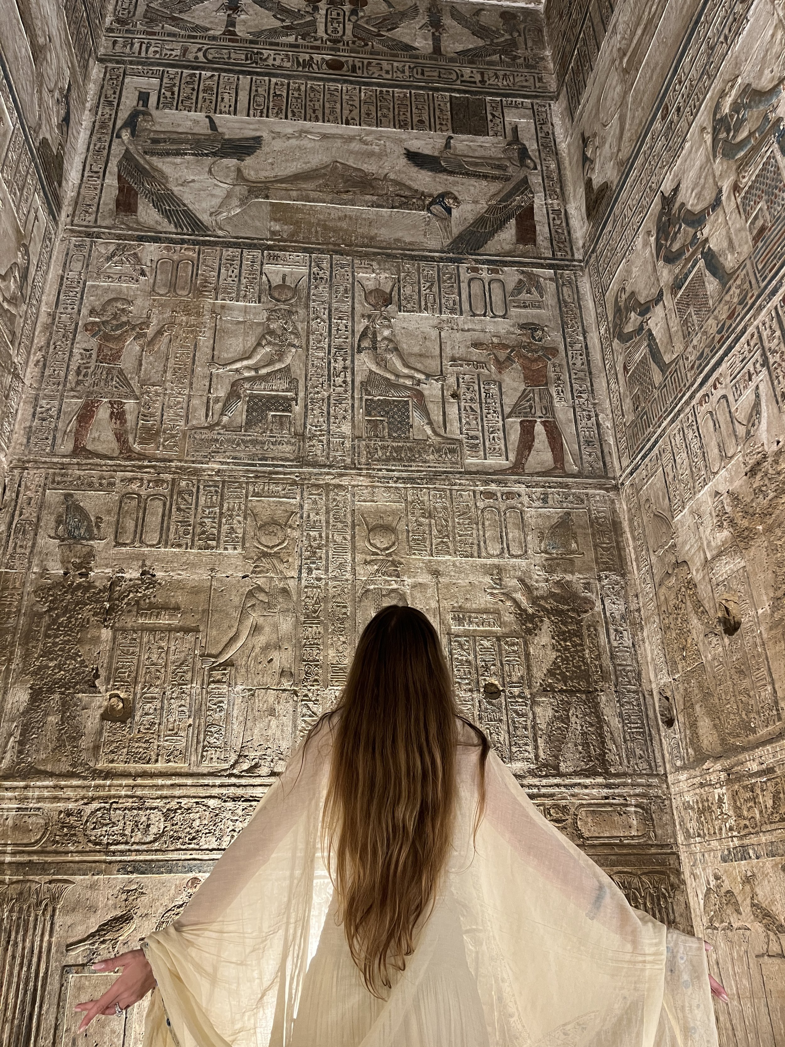 Woman standing inside an ancient Egyptian temple surrounded by sacred hieroglyphs inside Abydos temple during a spiritual initiation journey.