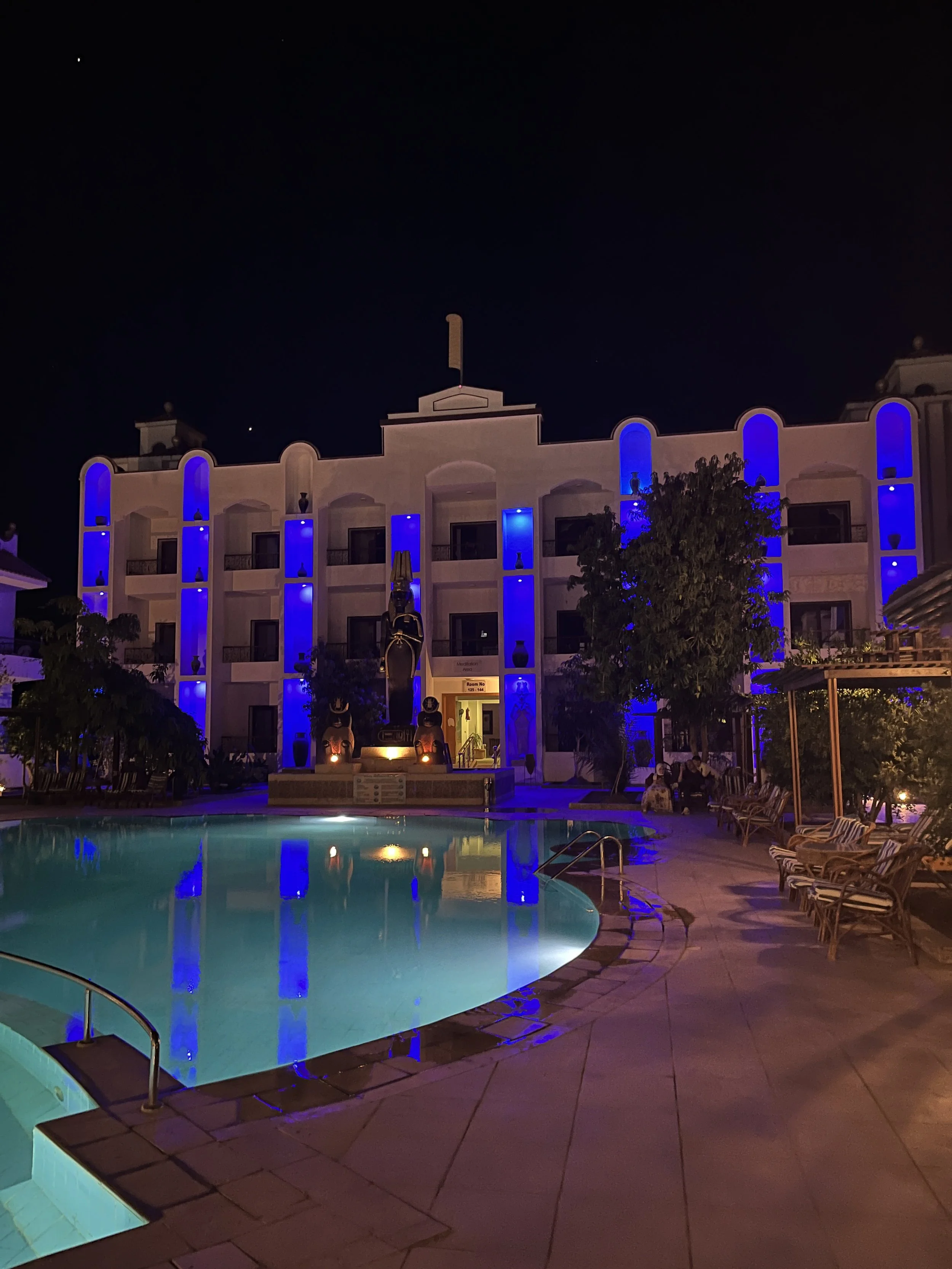 House of Life hotel and healing centre in Abydos at night with blue lighting and illuminated pool under a crescent moon