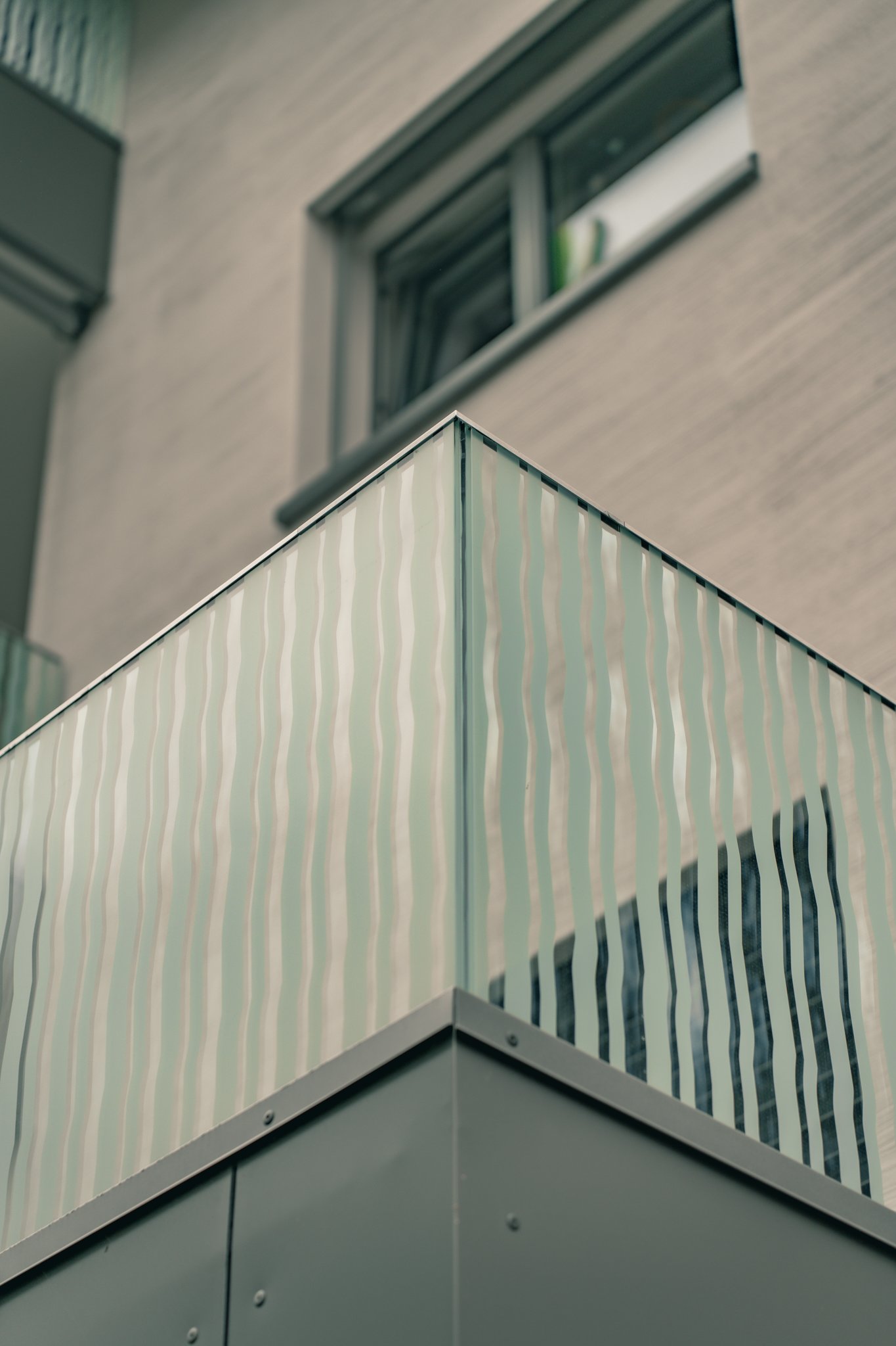 Moderne Gebäudefassade mit Glasbalkon, gewelltes Muster auf dem Glas