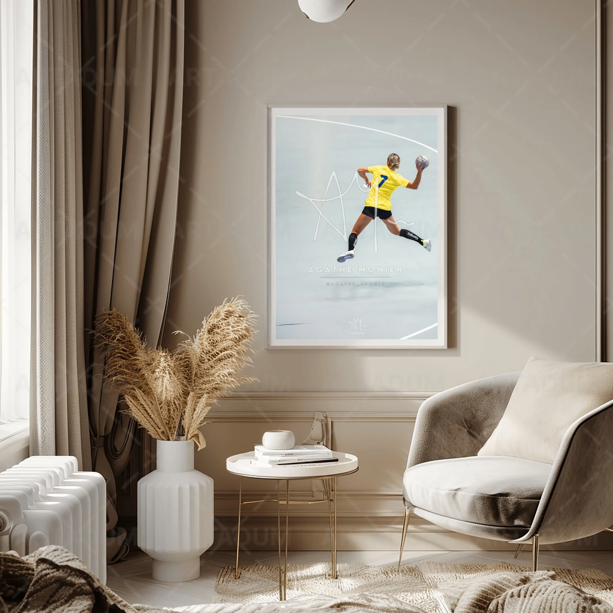 Une pièce de salon élégante avec un fauteuil beige, une table ronde blanche avec des livres et une petite décoration, un grand vase blanc avec des pampas séchées, et une toile d'art représentant un joueur de handball en jaune en plein saut avec un ballon.