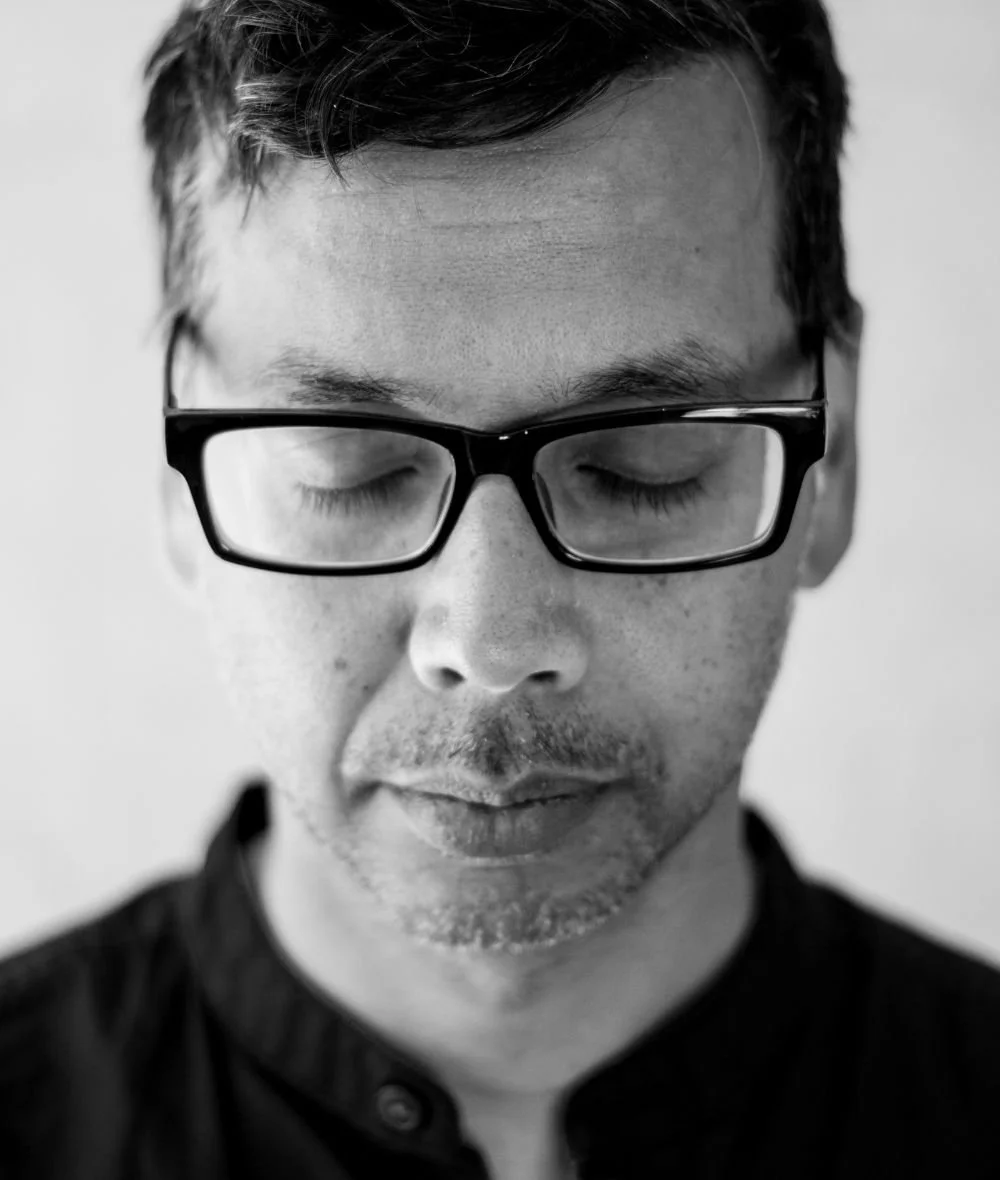 Black and white portrait of a man with glasses and closed eyes