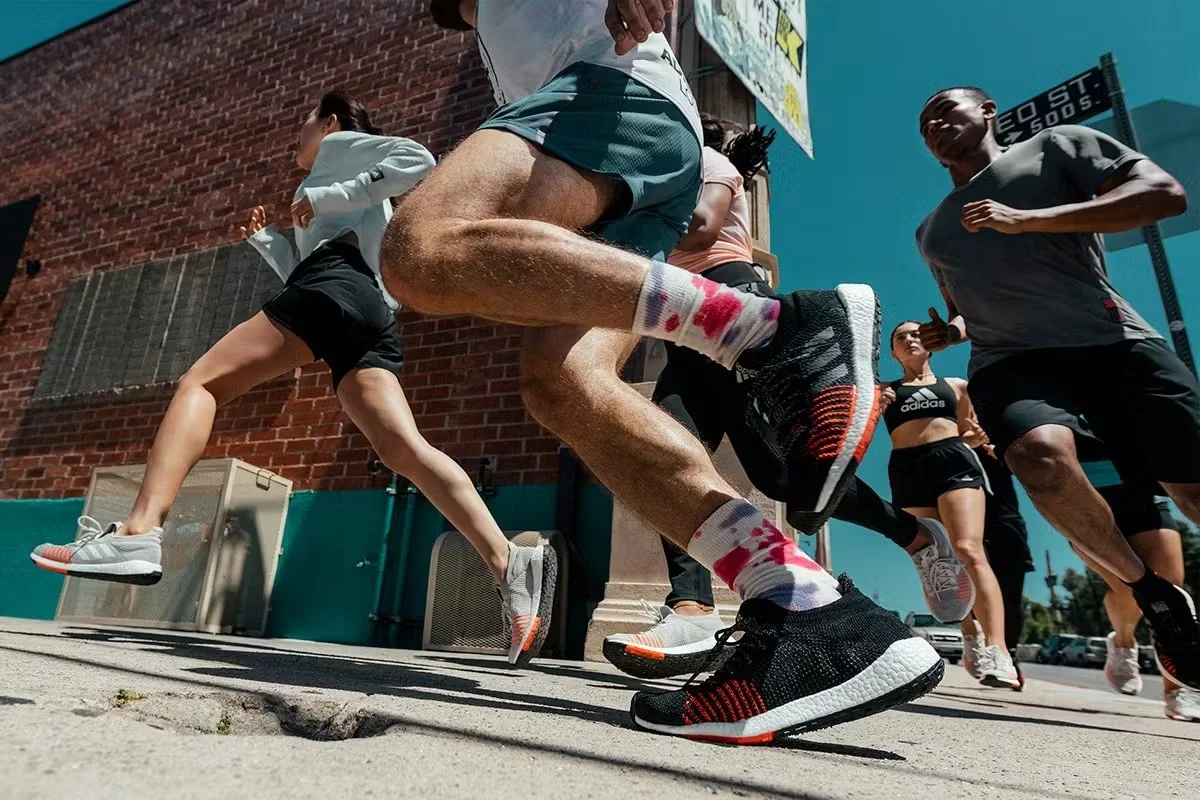 Group of people jogging outdoors in athletic gear on a sunny day.