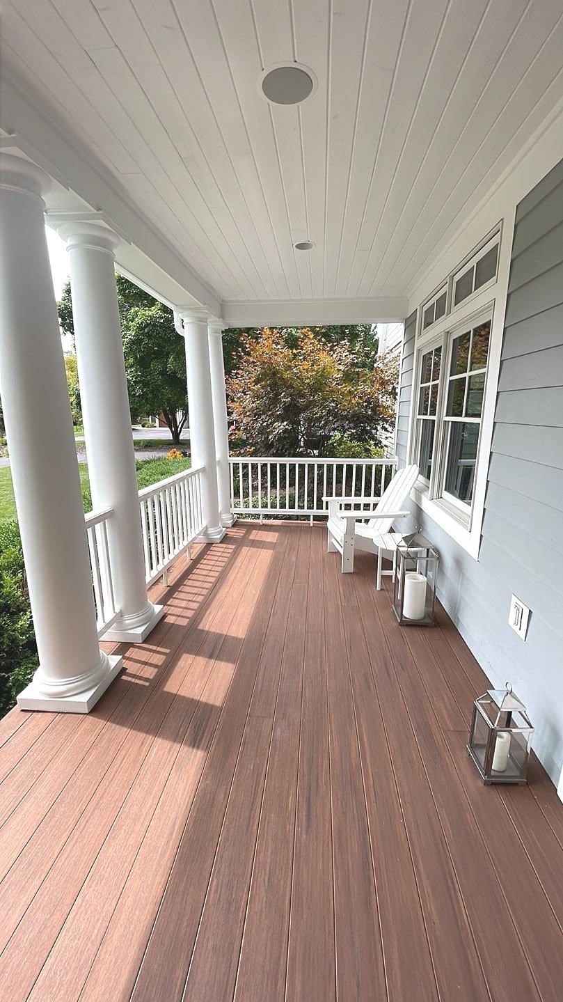 This beautifully crafted covered porch features a warm, low-maintenance composite floor paired with classic white railings and elegant column details. The inviting design offers a spacious layout perfect for relaxing or entertaining, enhanced by coz