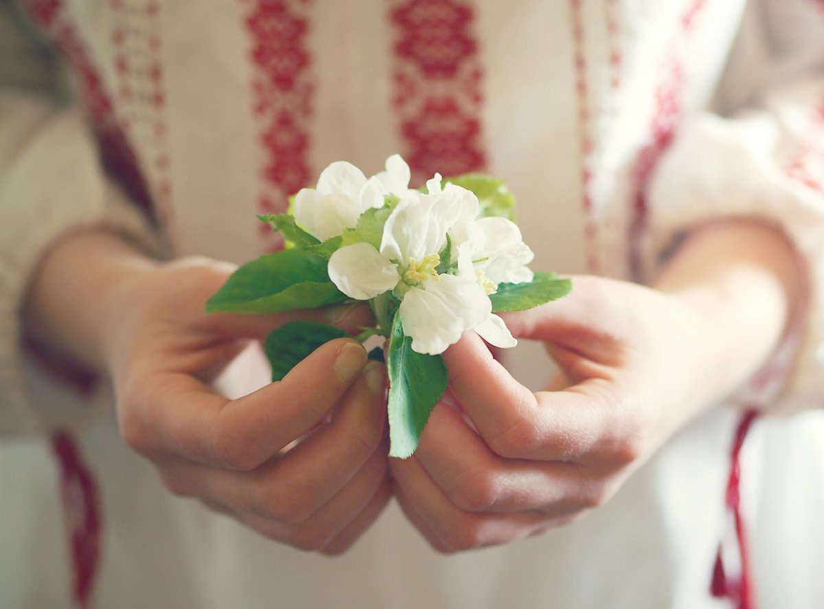 Person holding a small bouquet of white flowers with green leaves