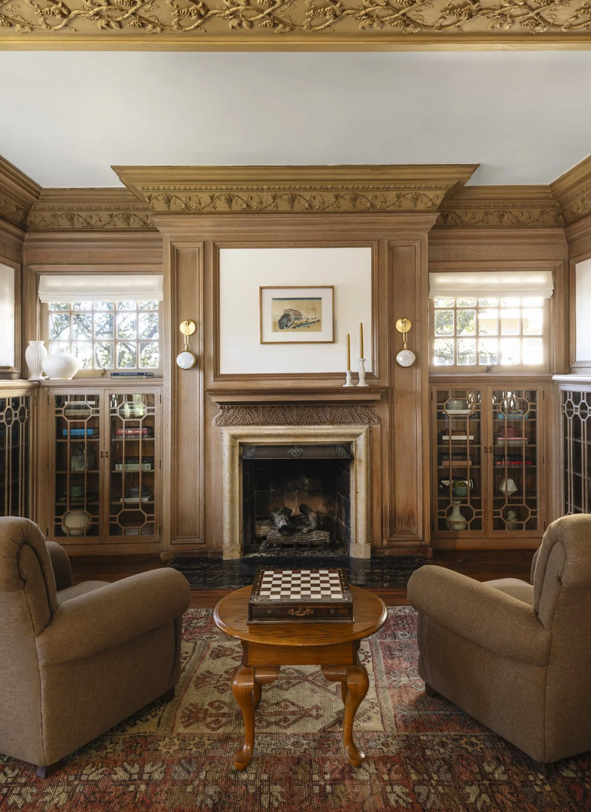 San Francisco living room with a restored wood fireplace, custom built-in bookcases, original millwork, hardwood floors, and large windows that bring in abundant natural light.