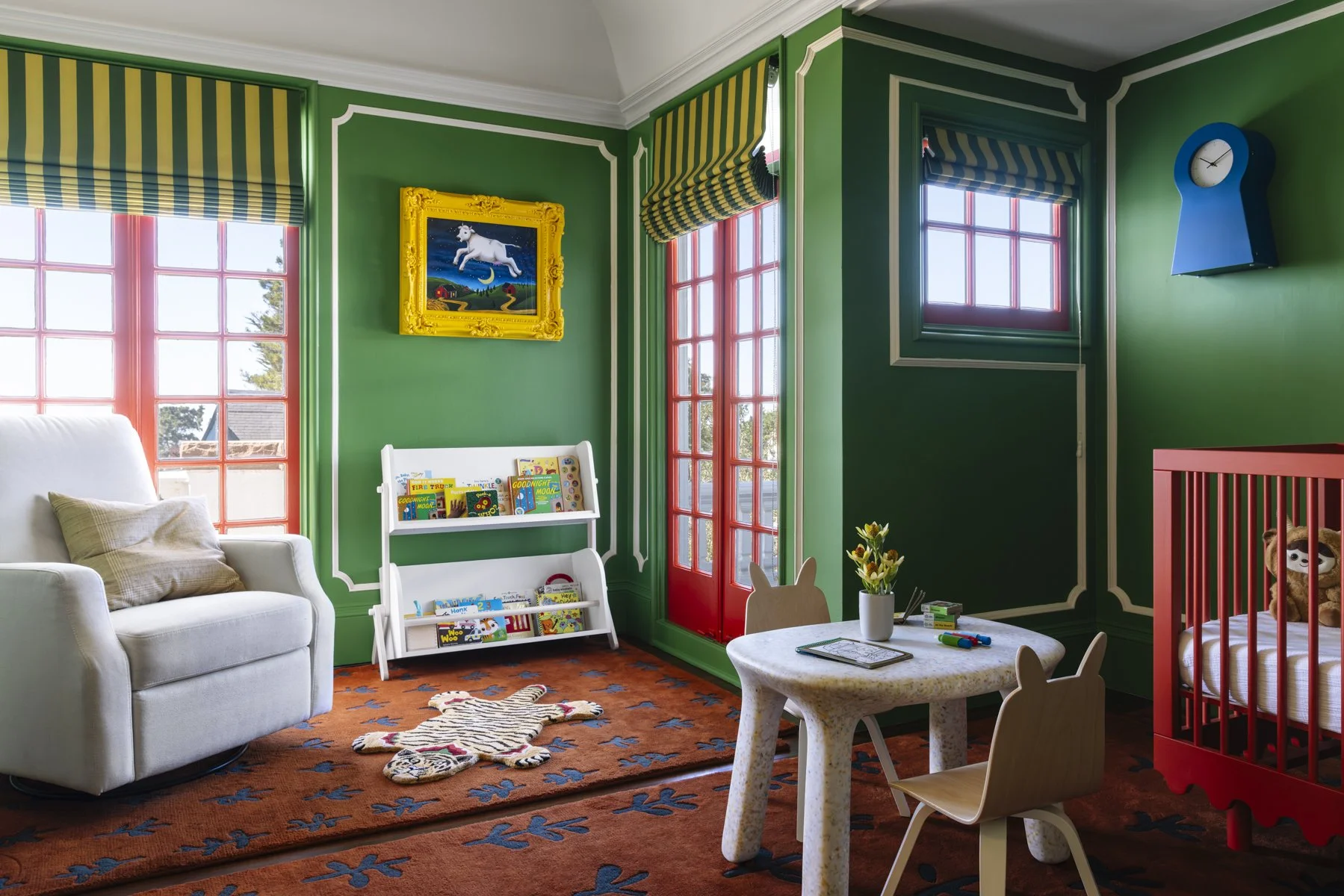 Custom children's bedroom featuring bold green walls, red-framed windows, a reading nook, custom Roman shades, a nursery crib, and playful designer furnishings in a renovated San Francisco home.