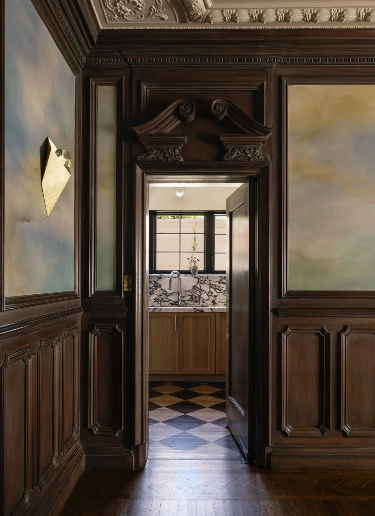 Custom wood millwork and an ornate doorway leading to a luxury kitchen with a marble backsplash in a San Francisco home. I