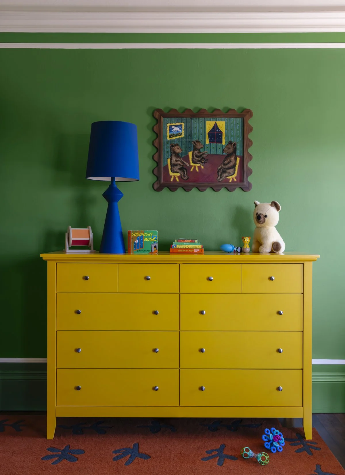 Colorful custom children's bedroom featuring a bright yellow dresser, bold green walls, playful artwork, children's books, and designer decor in a renovated San Francisco home.