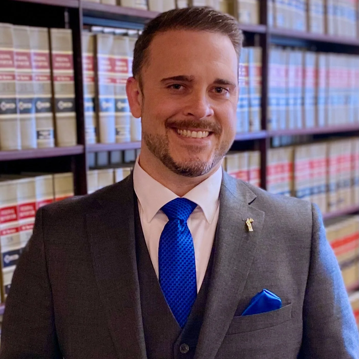 Attorney C. Scott Jones standing in front of law books in his Memphis office, wearing a gray suit and blue tie.
