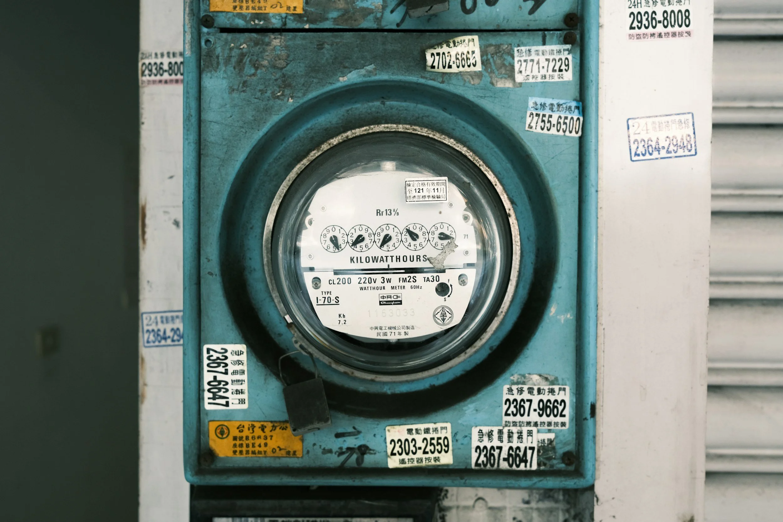 An old, weathered electric meter with multiple stickers and labels in Chinese characters.