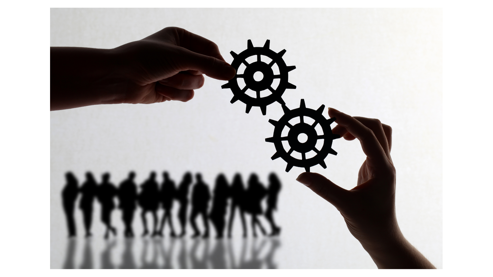 Two hands hold silhouettes of interlocking gears with a group of people in shadow reflection below.