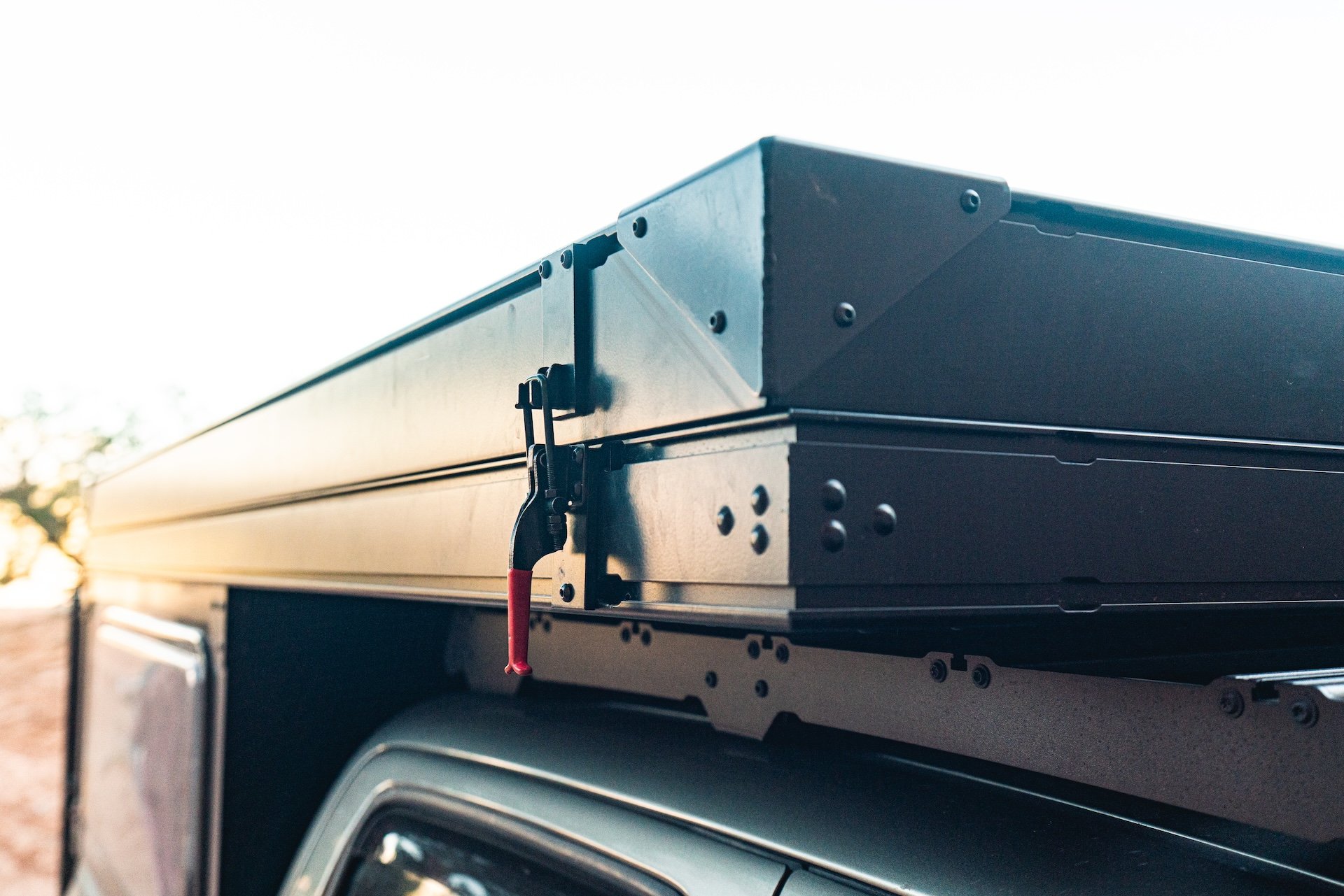 Close-up of a folded rooftop tent mounted on a vehicle.