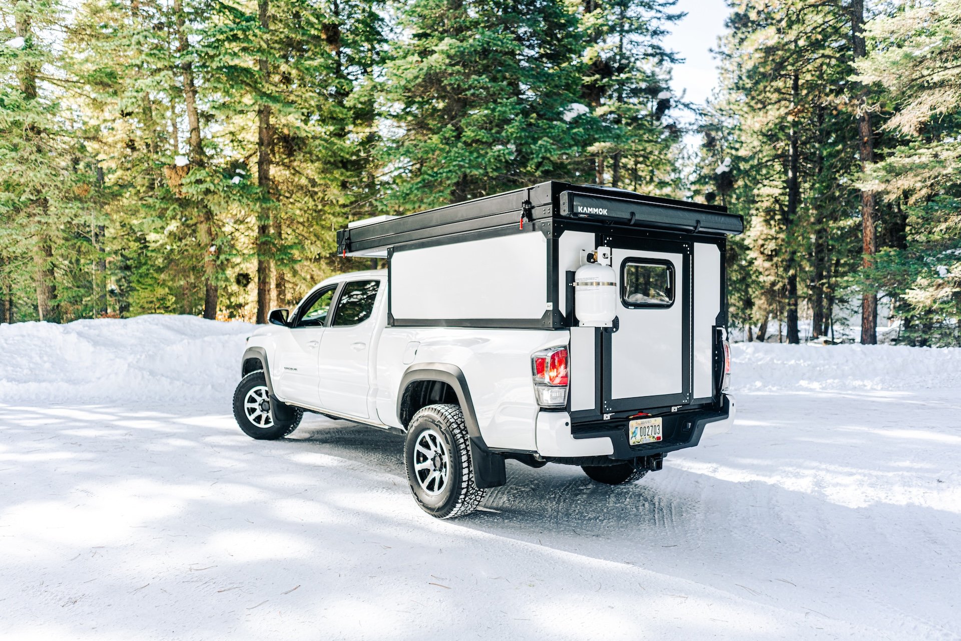 White pickup truck with a camper shell in snowy forest