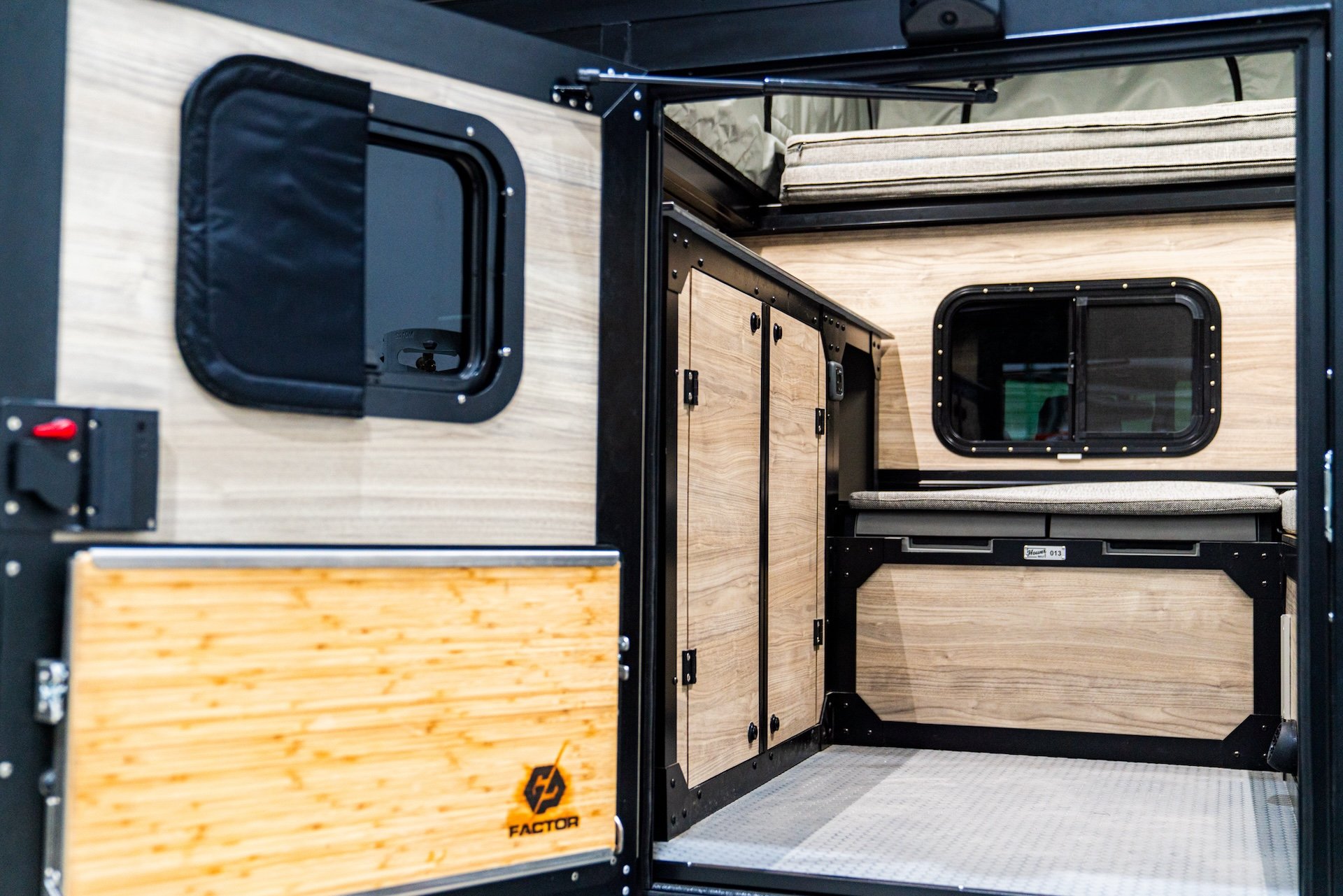 Interior of a camper trailer with wood paneling, storage cabinets, and cushioned seating.