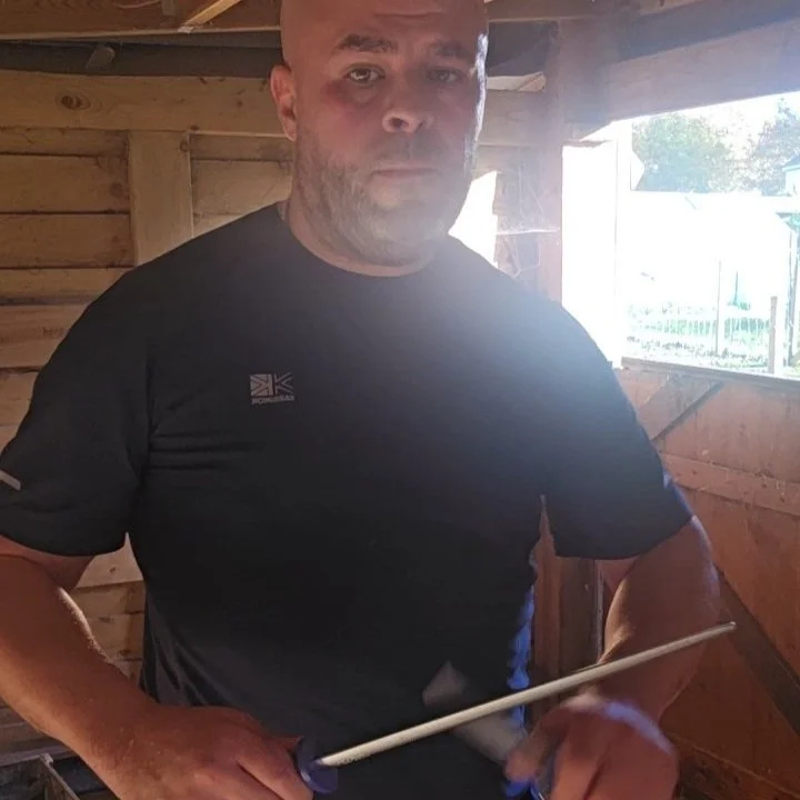 Slaughterman standing in the butchery area holding a sharpening steel and sharpening a knife used for processing livestock