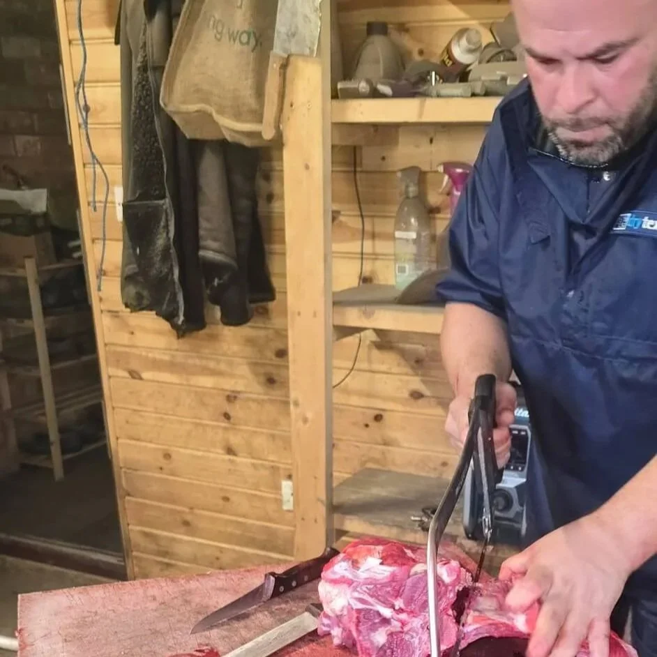 Richard, mobile slaughterman using a meat saw to cut a goat carcass