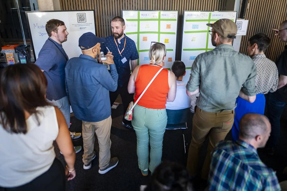 Participants look at boards with sessions ideas on sticky notes