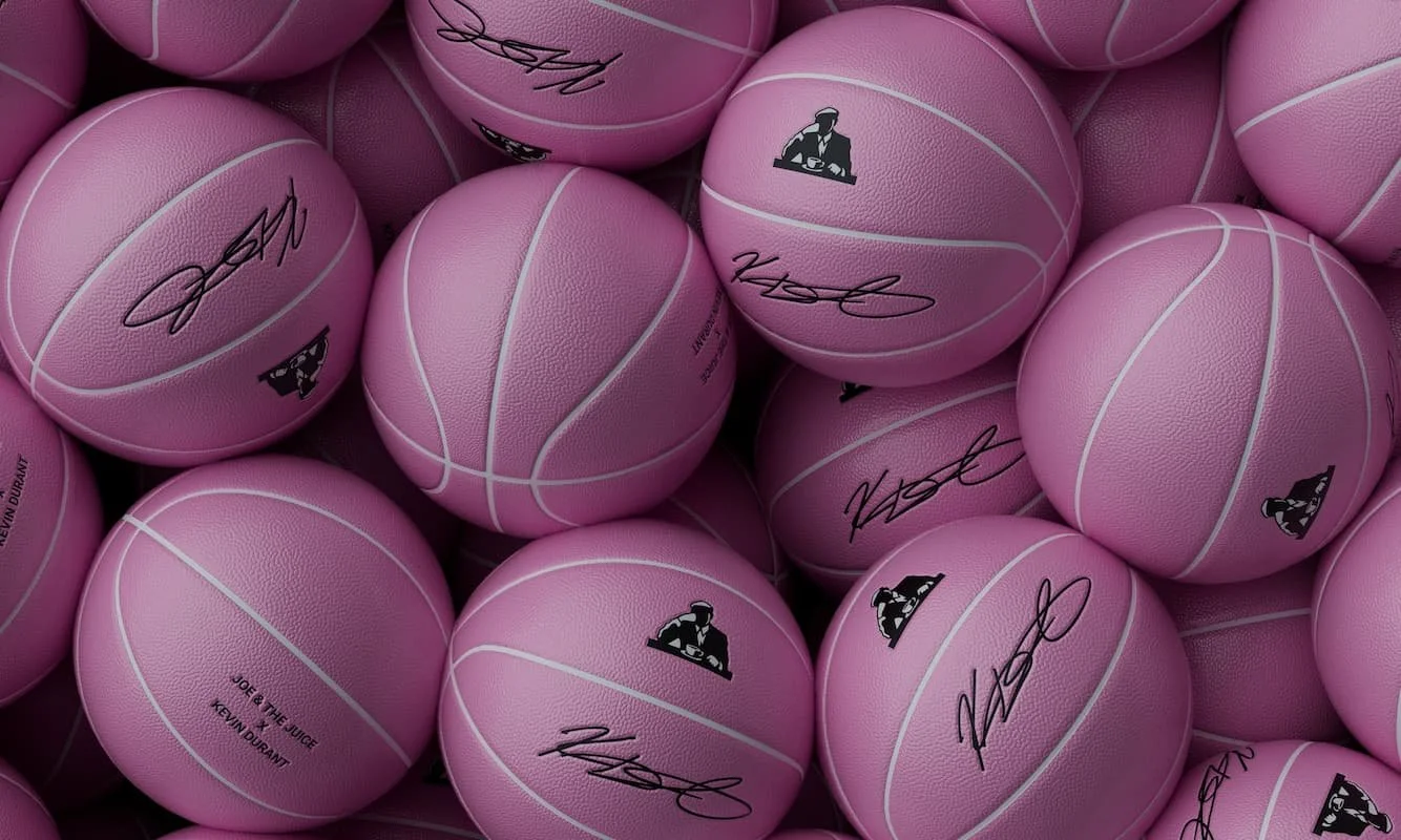 Pink basketballs with signatures and logos stacked together.