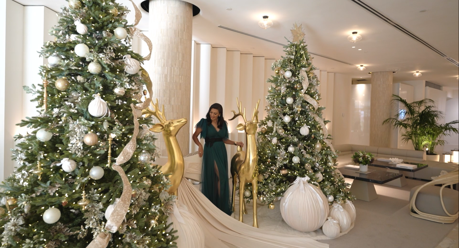 A high-fashion holiday layout inside a prestigious lobby, where towering, expertly curated Christmas trees create a dramatic, glowing winter wonderland.