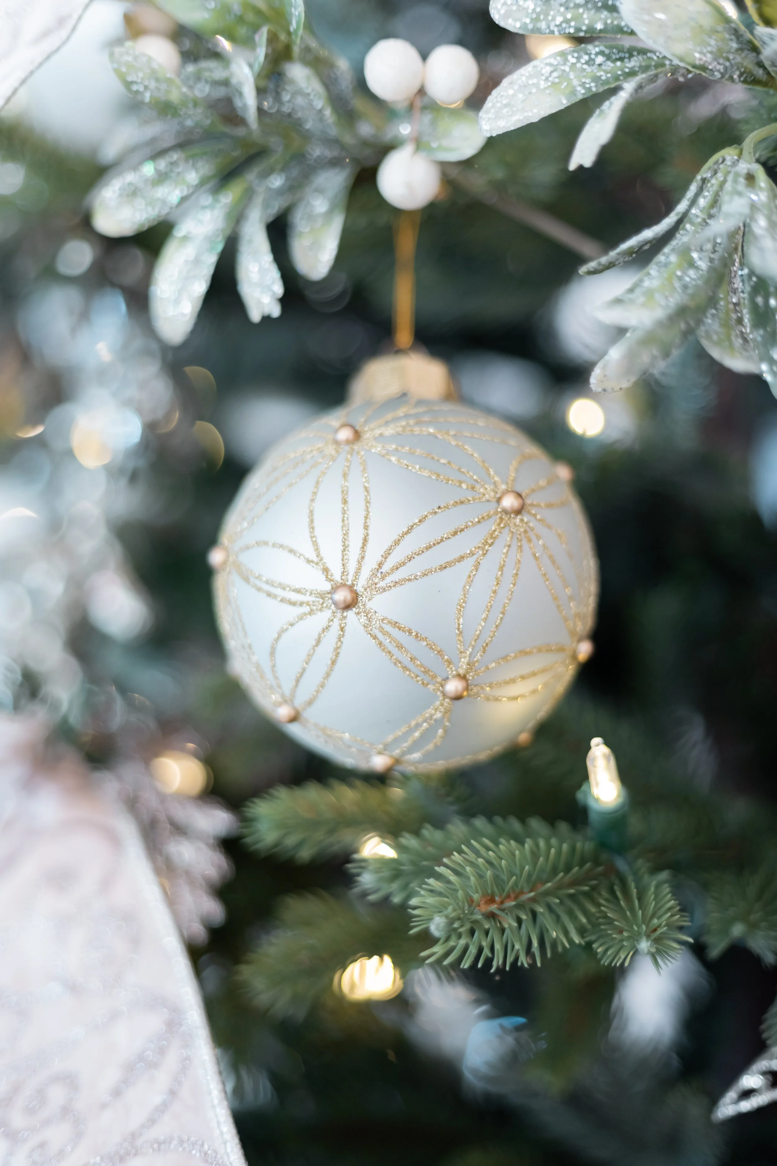 An exquisite close-up of a designer porcelain sphere, meticulously filigreed with geometric gold patterns and delicate pearl accents.