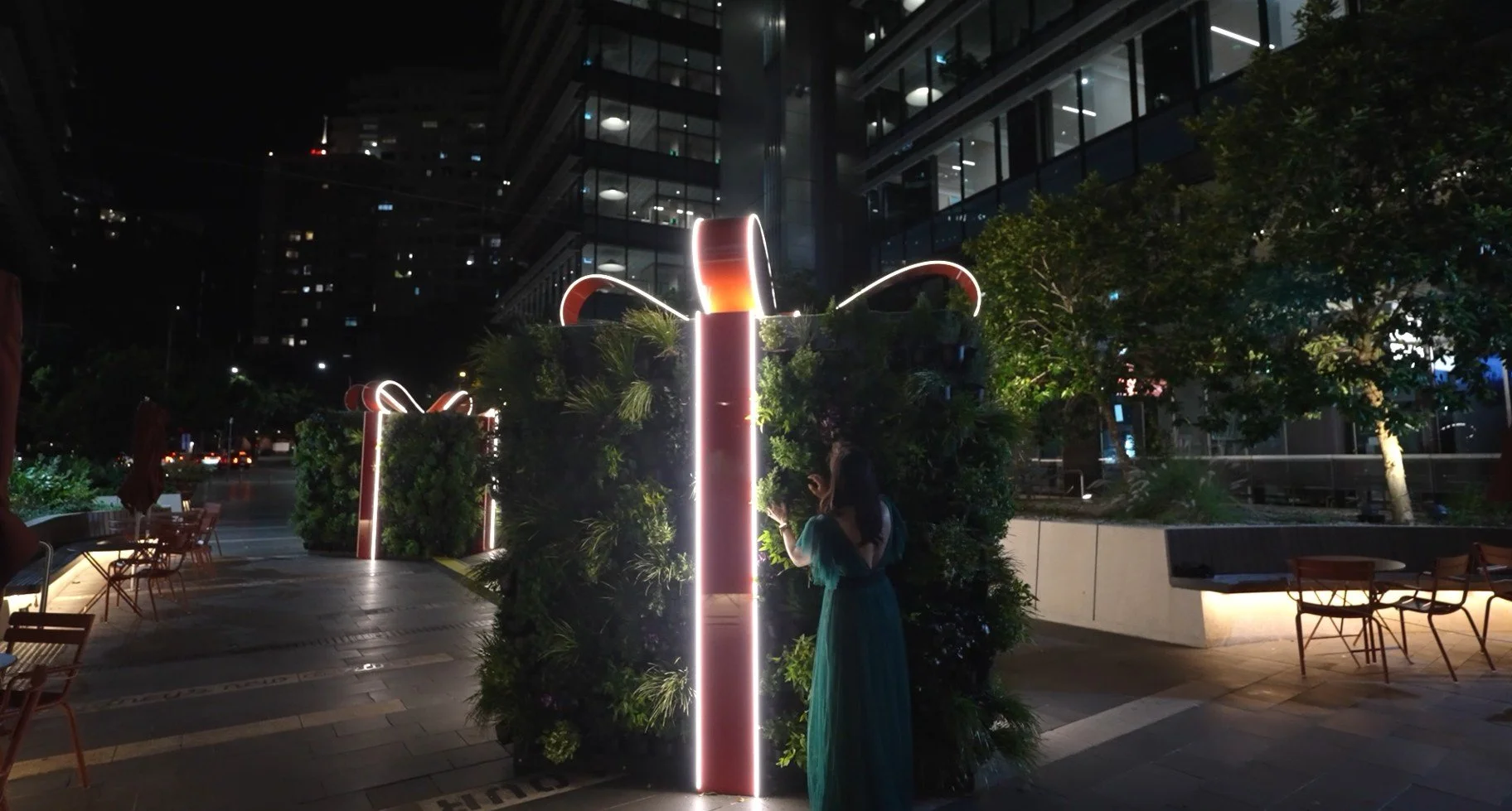 Innovative botanical holiday structures topped with bold red ribbons, spreading festive cheer throughout Darling Quarter.
