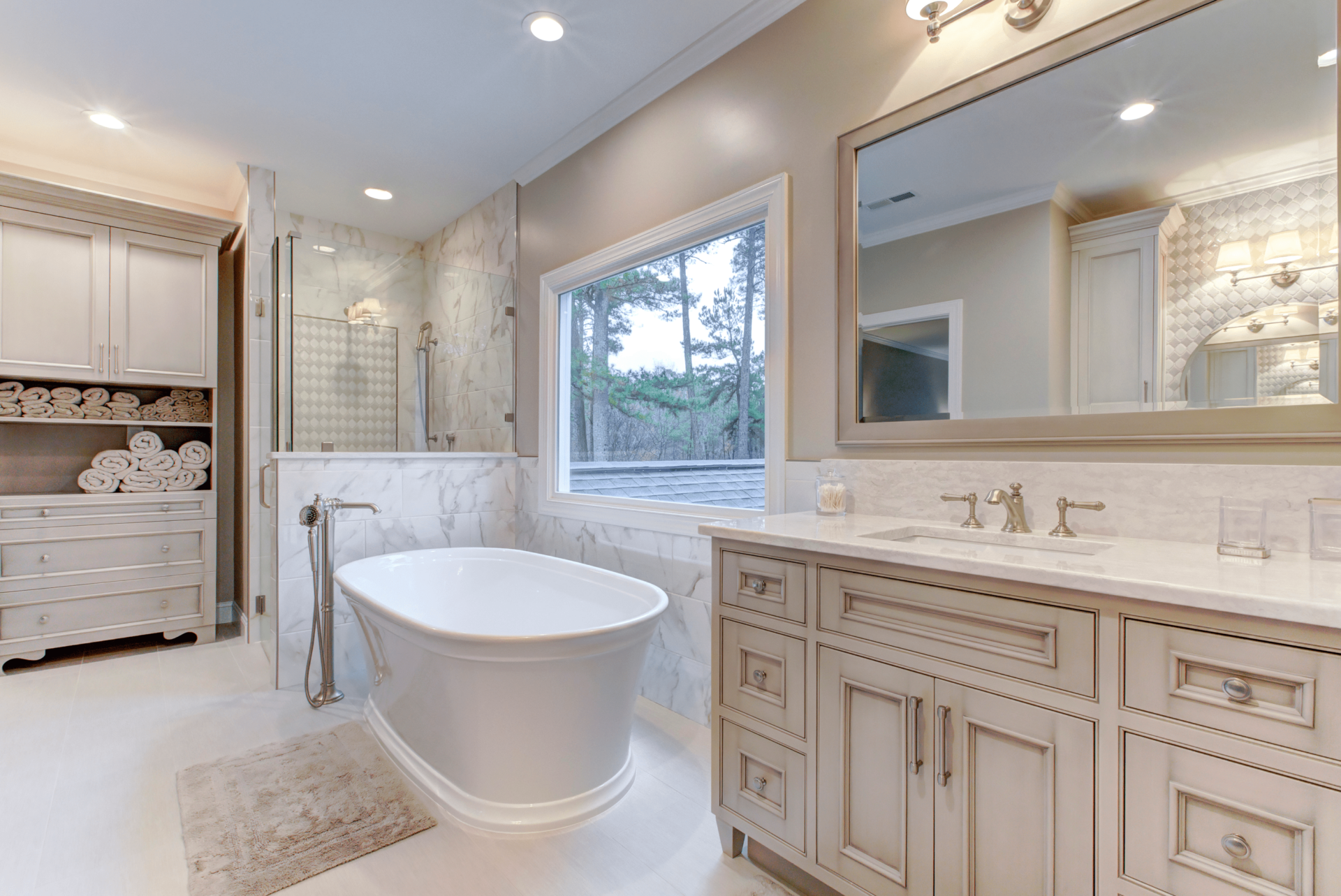 Luxurious bathroom with a freestanding bathtub, marble tiles, large mirror, vanity with dual sinks, and shelving with rolled towels.