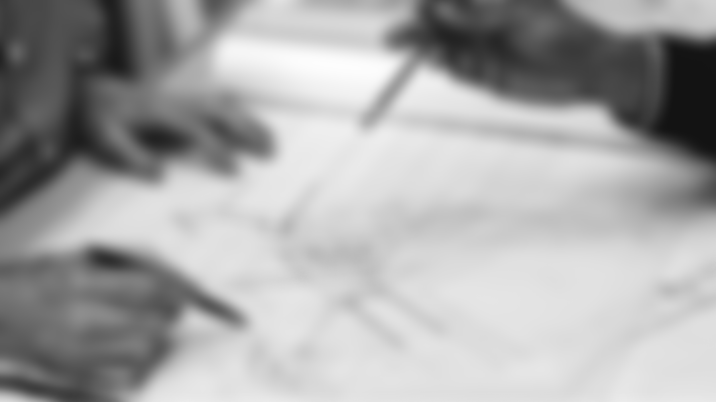 Background photo of Steve Woods, Landscape Architect, working at a desk with sketch drawing below his hand