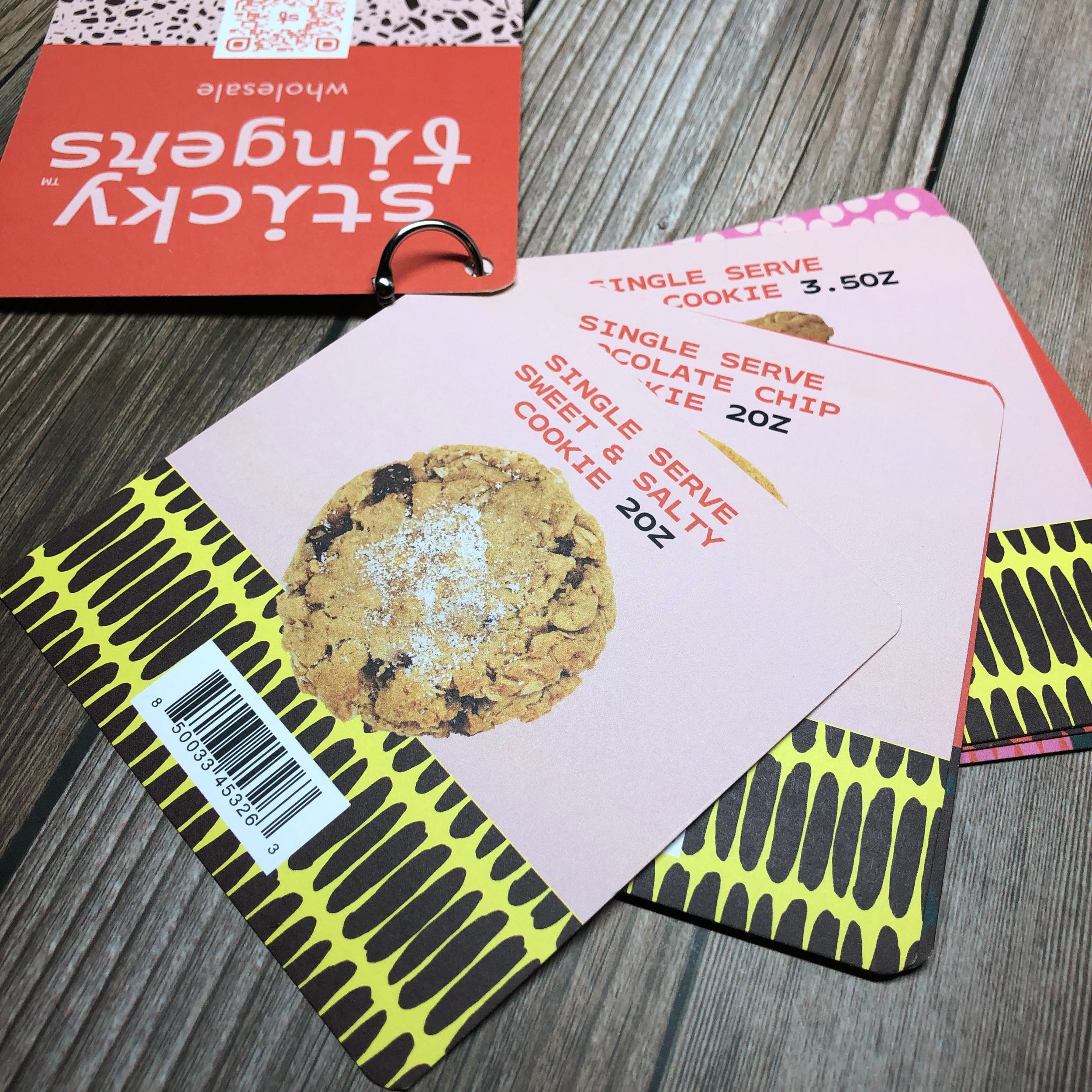 Menu pages featuring cookies and snacks, placed on a wooden surface, with a visible barcode at the bottom of the page.