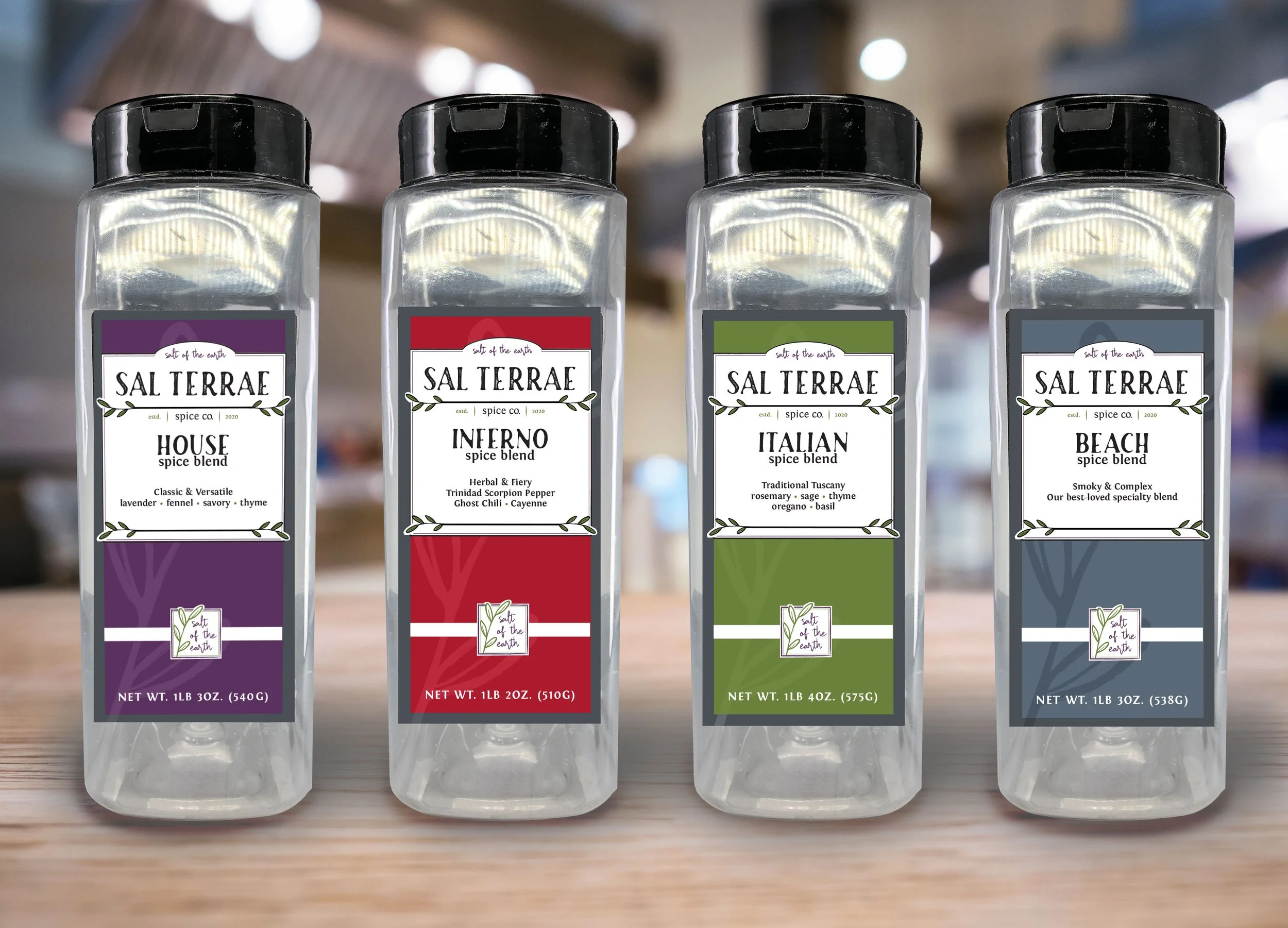 Four bottles of salt from the brand Salt of the Earth with different flavors: House, Inferno, Italian, and Beach, placed on a wooden surface in a store.