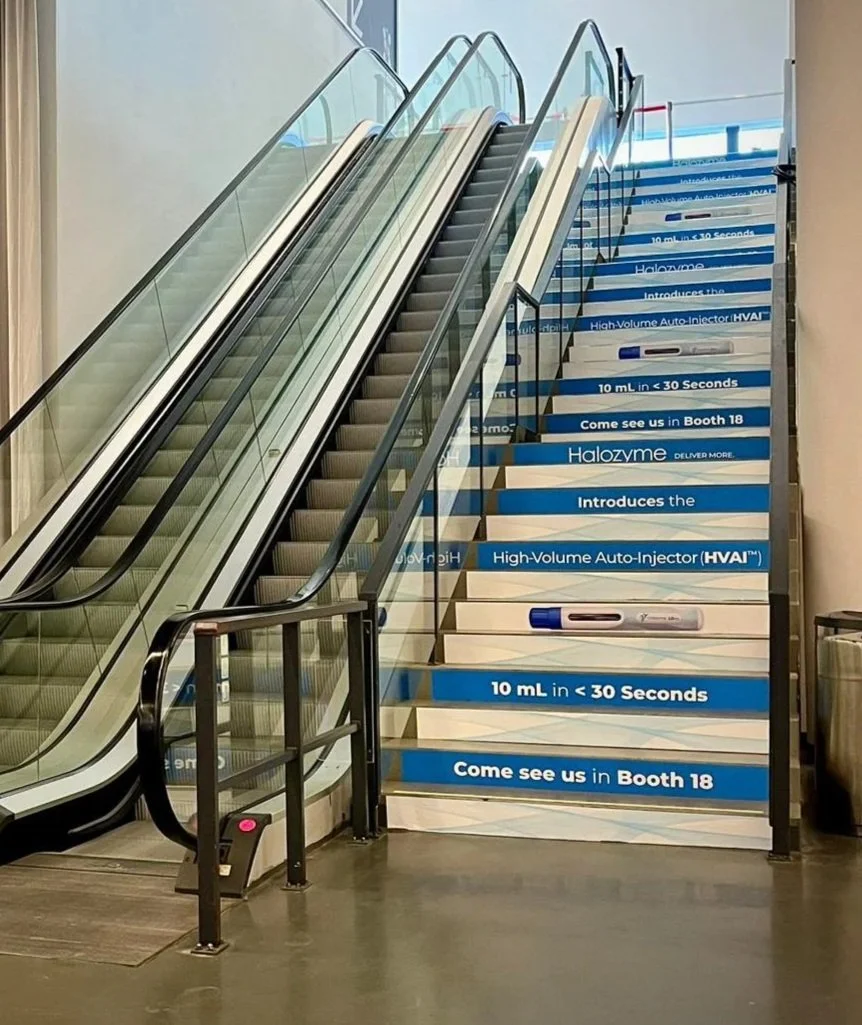 An escalator and a staircase in an indoor space with blue signage and a beige curtain on the side.