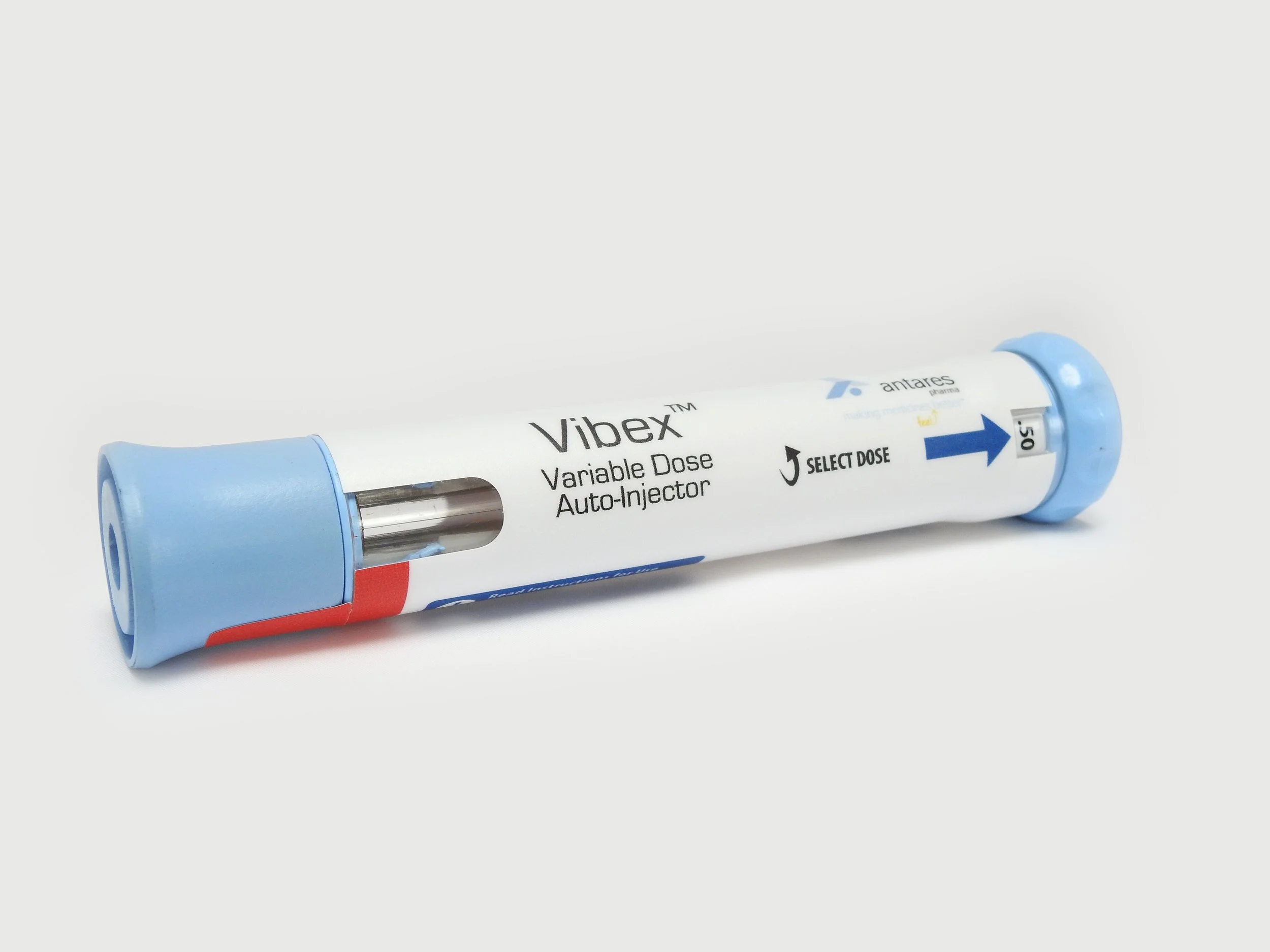 A Vibex variable dose auto-injector medical device with blue caps at both ends and white body, featuring instructions, an arrow, and a window showing medication inside.