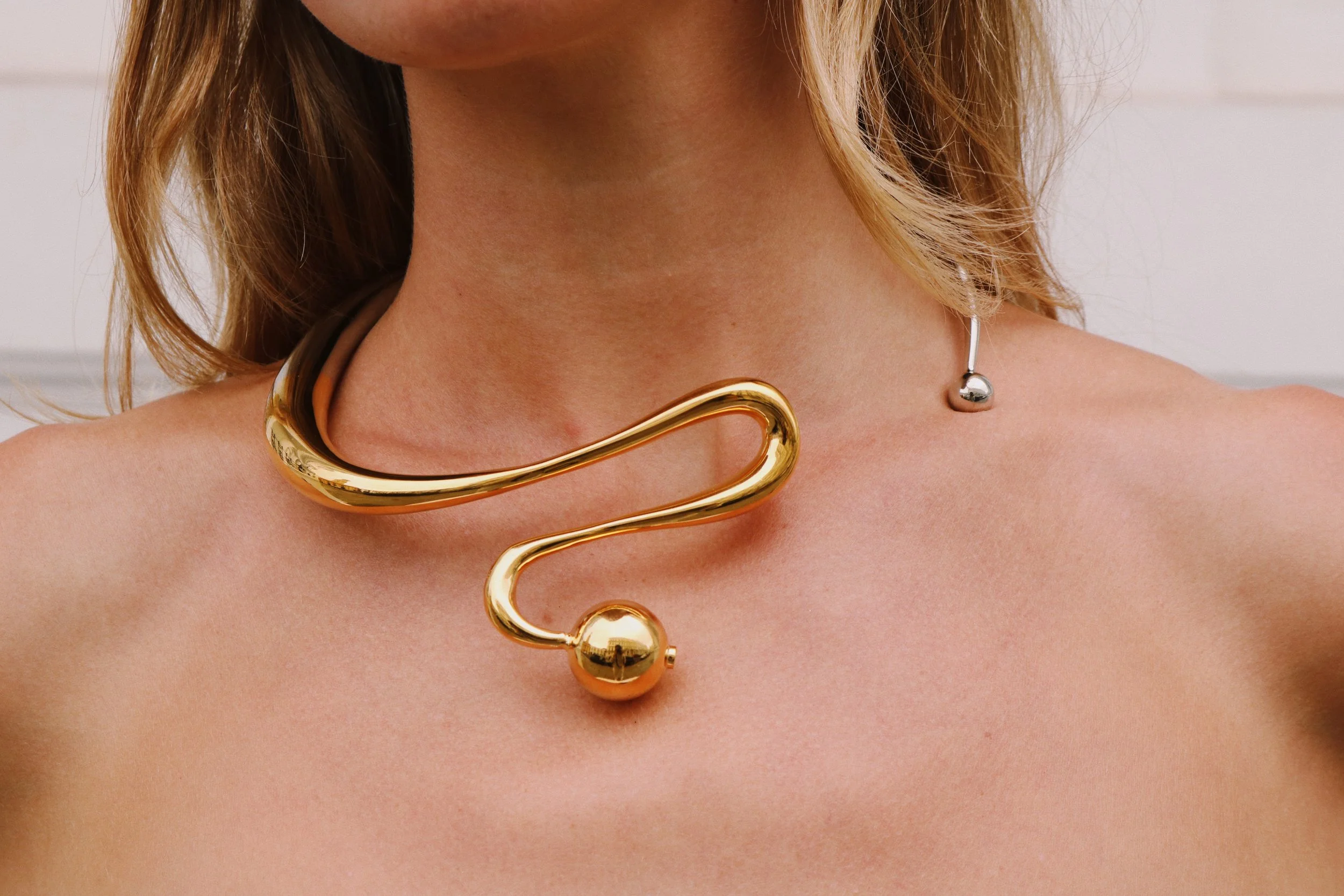 Unique gold necklace with abstract design worn around a woman's neck.