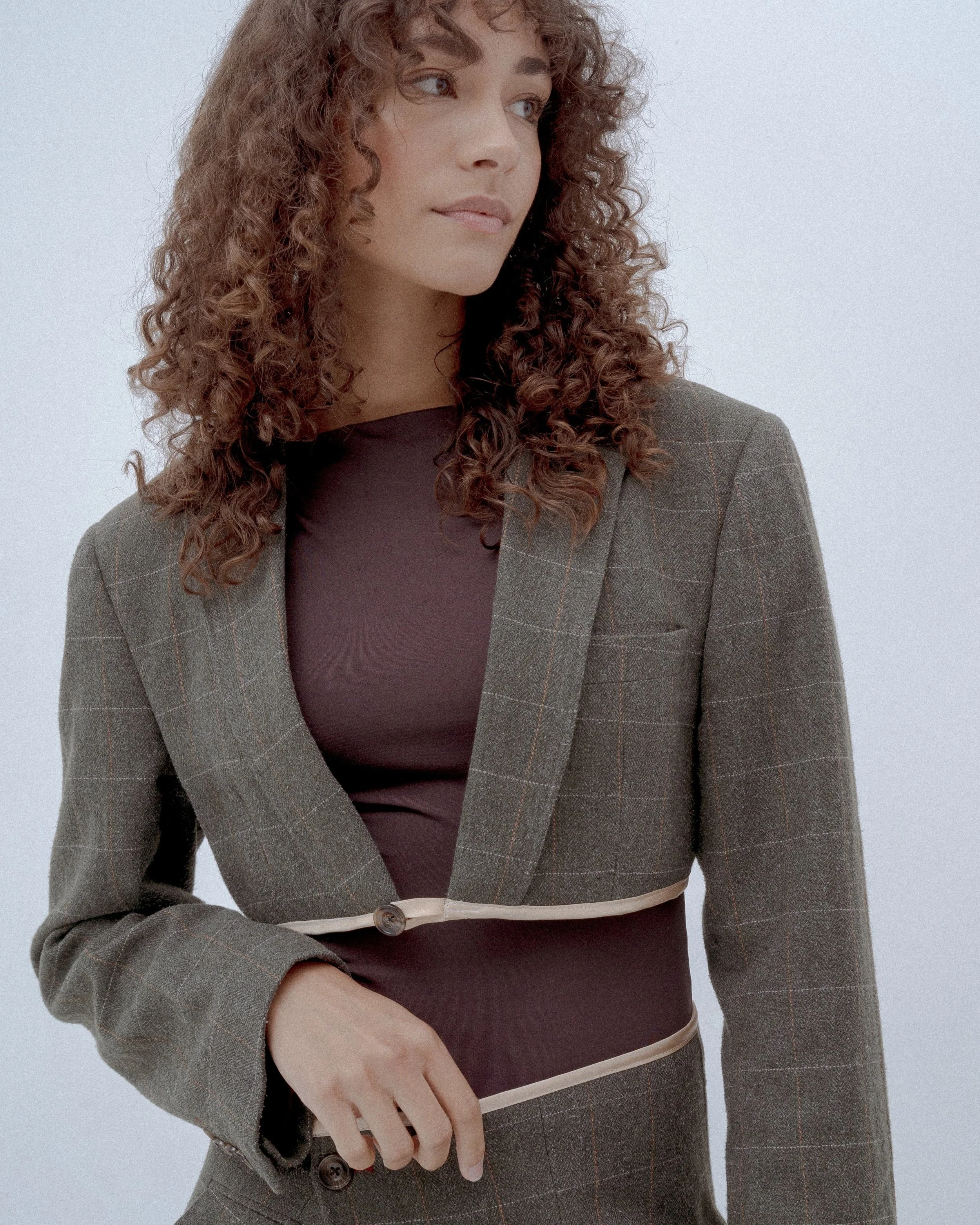 Woman wearing a plaid crop jacket over a brown top