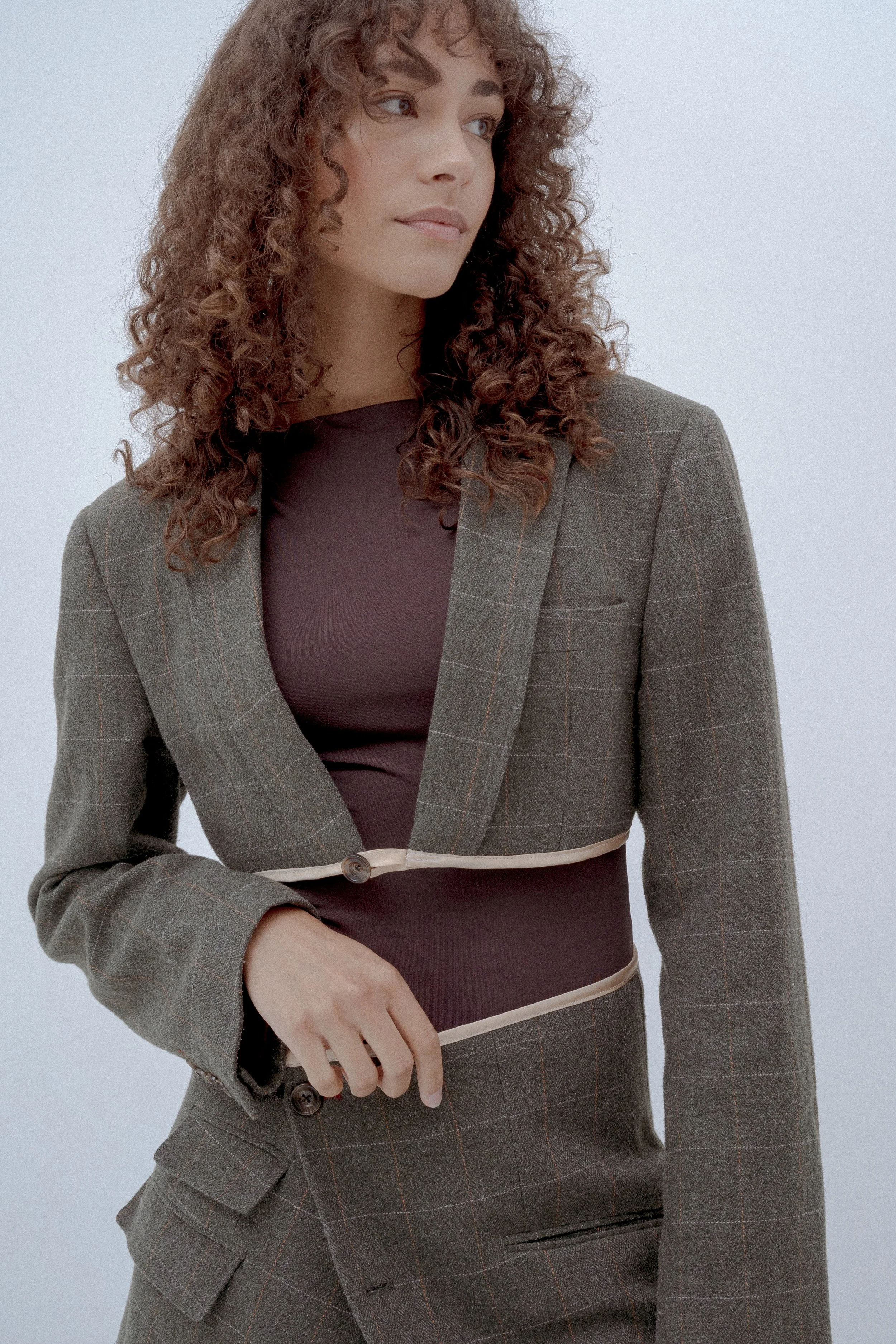 Person wearing a plaid cropped blazer over a brown top