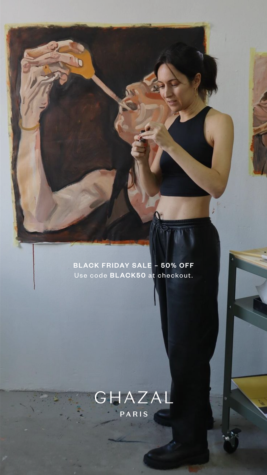 Artist standing in front of a painting, wearing black crop top and pants, with "Black Friday Sale - 50% Off" text overlay; "Ghazal Paris" branding visible.